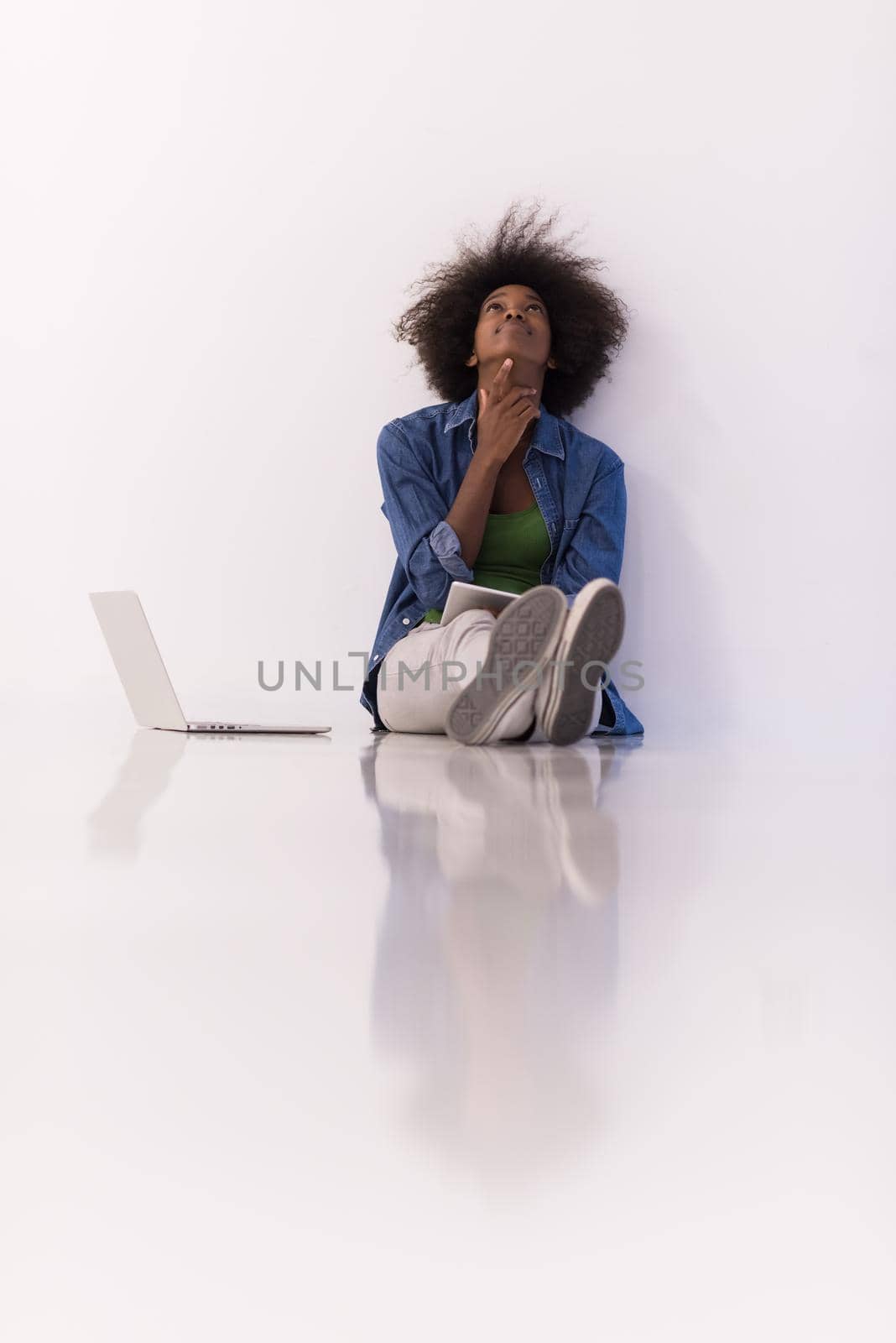 african american woman sitting on floor with laptop by dotshock