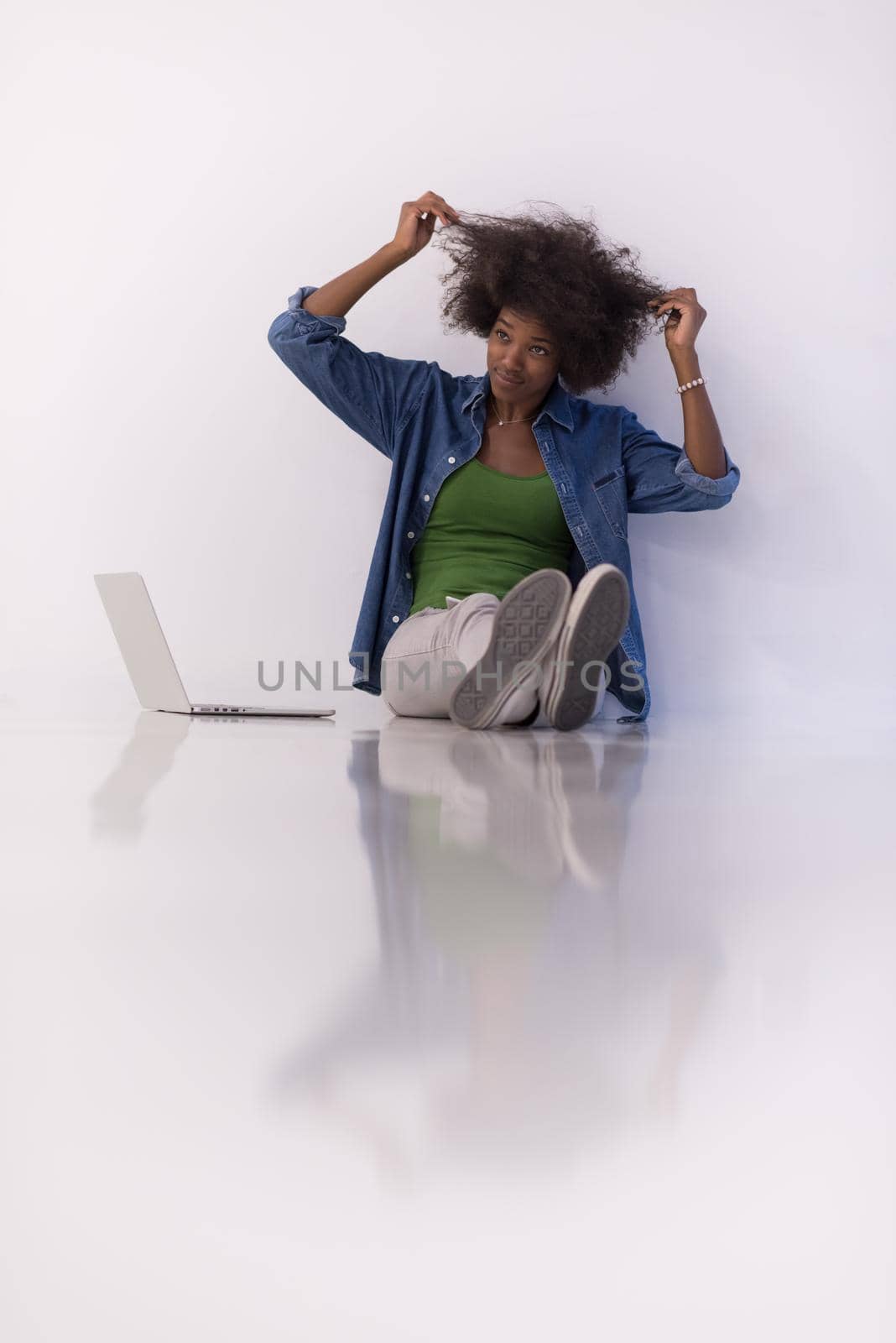 african american woman sitting on floor with laptop by dotshock