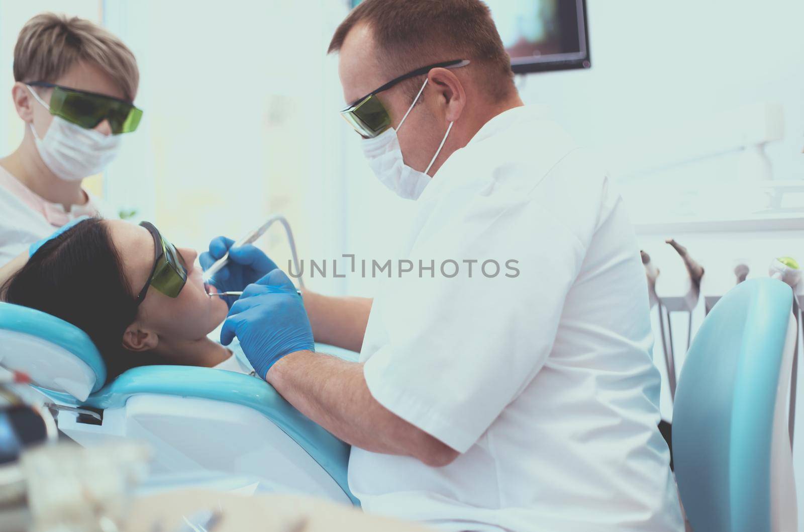 Man dentist working at his patients teeth.