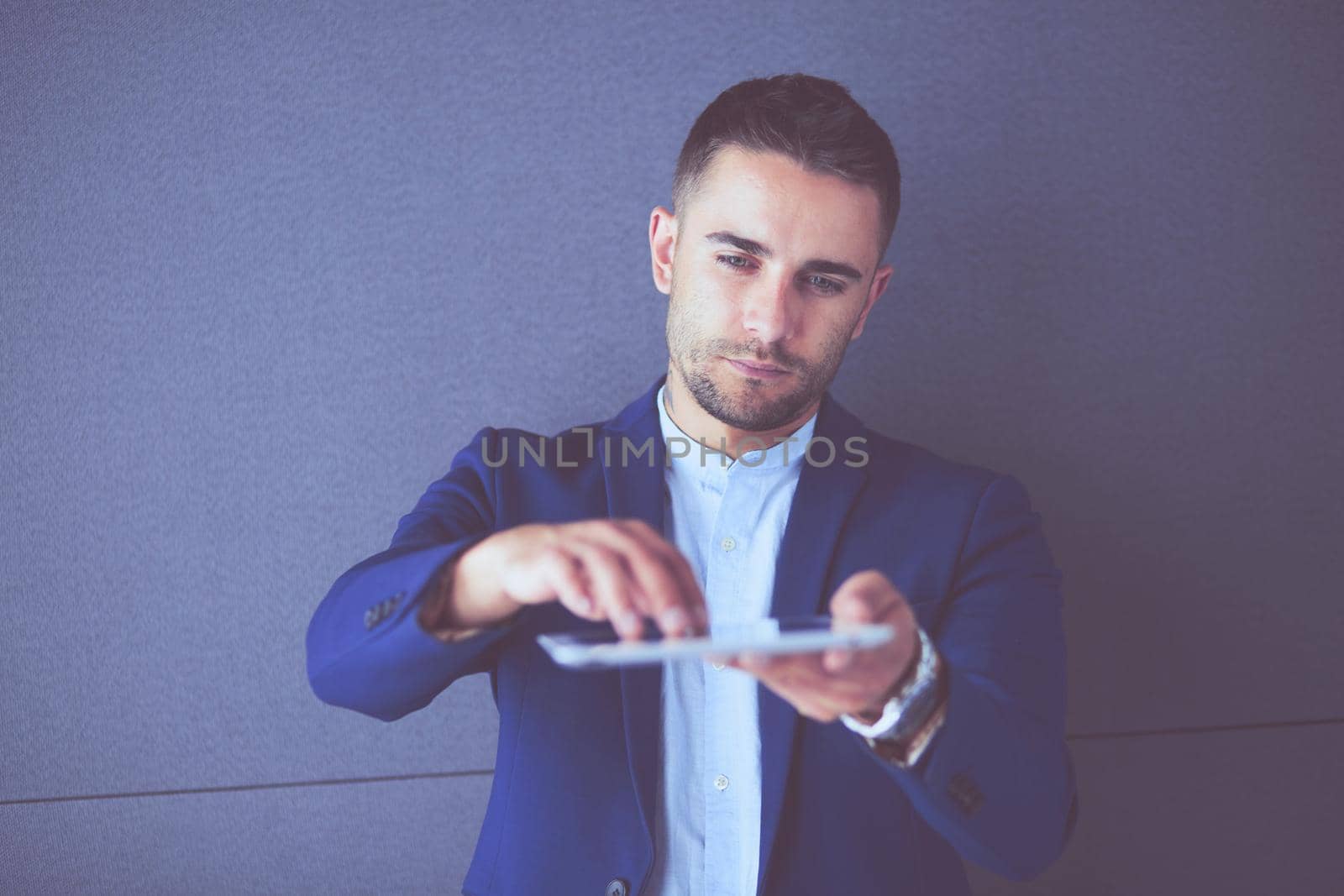 Young businessman sitting isolated on grey background