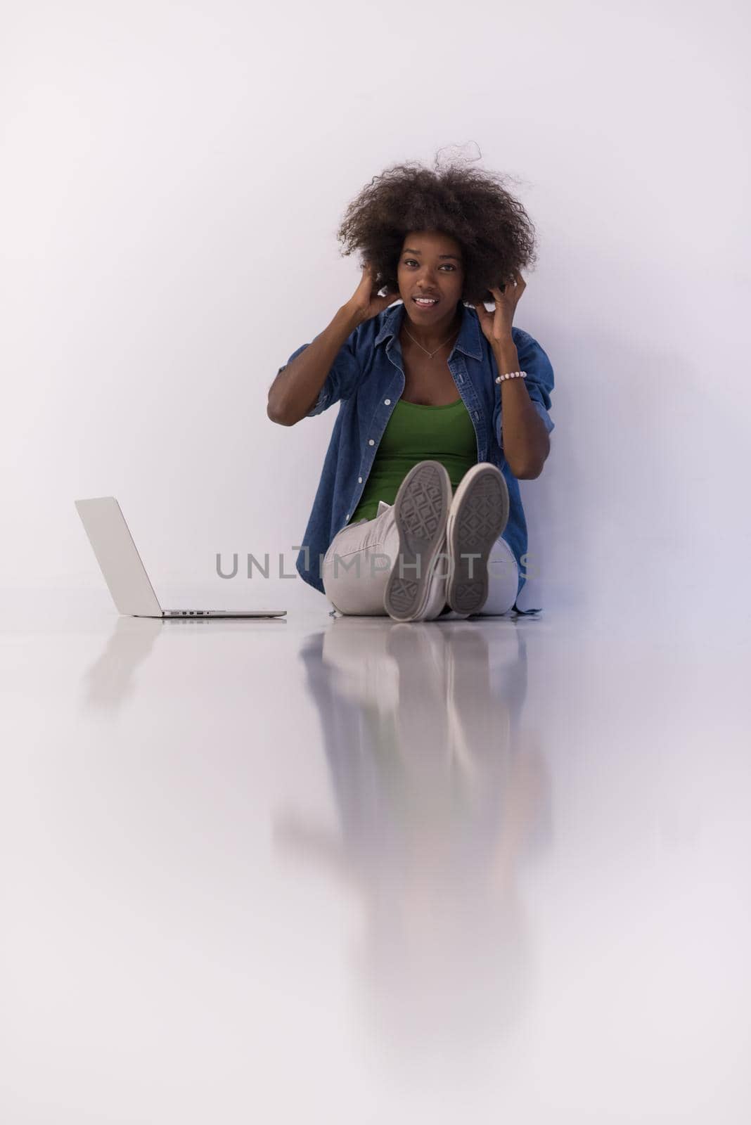 african american woman sitting on floor with laptop by dotshock