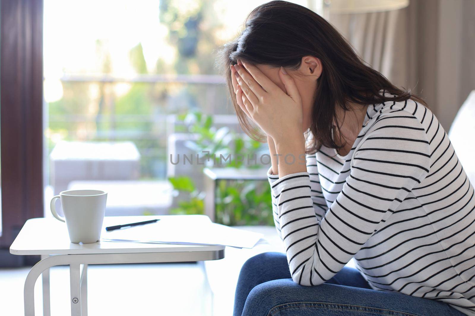 Sad woman with the bills sitting on a sofa in the living room