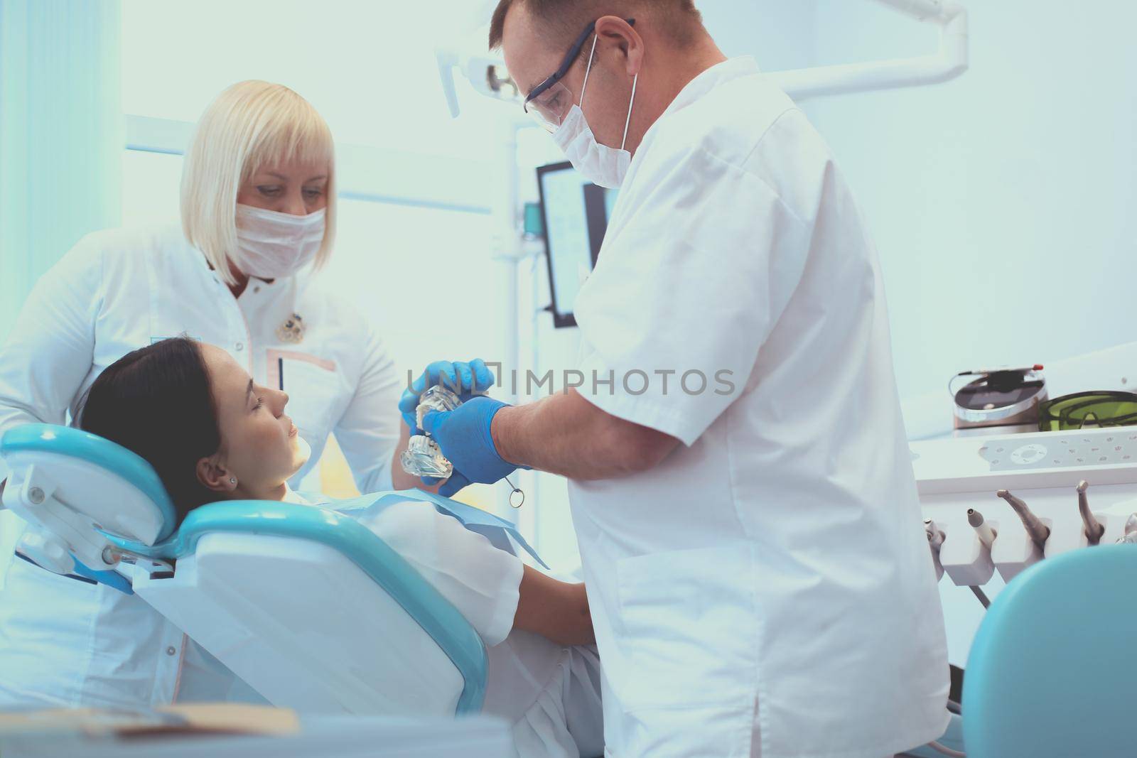 Male dentists examining and working on young female patient.Dentist's office