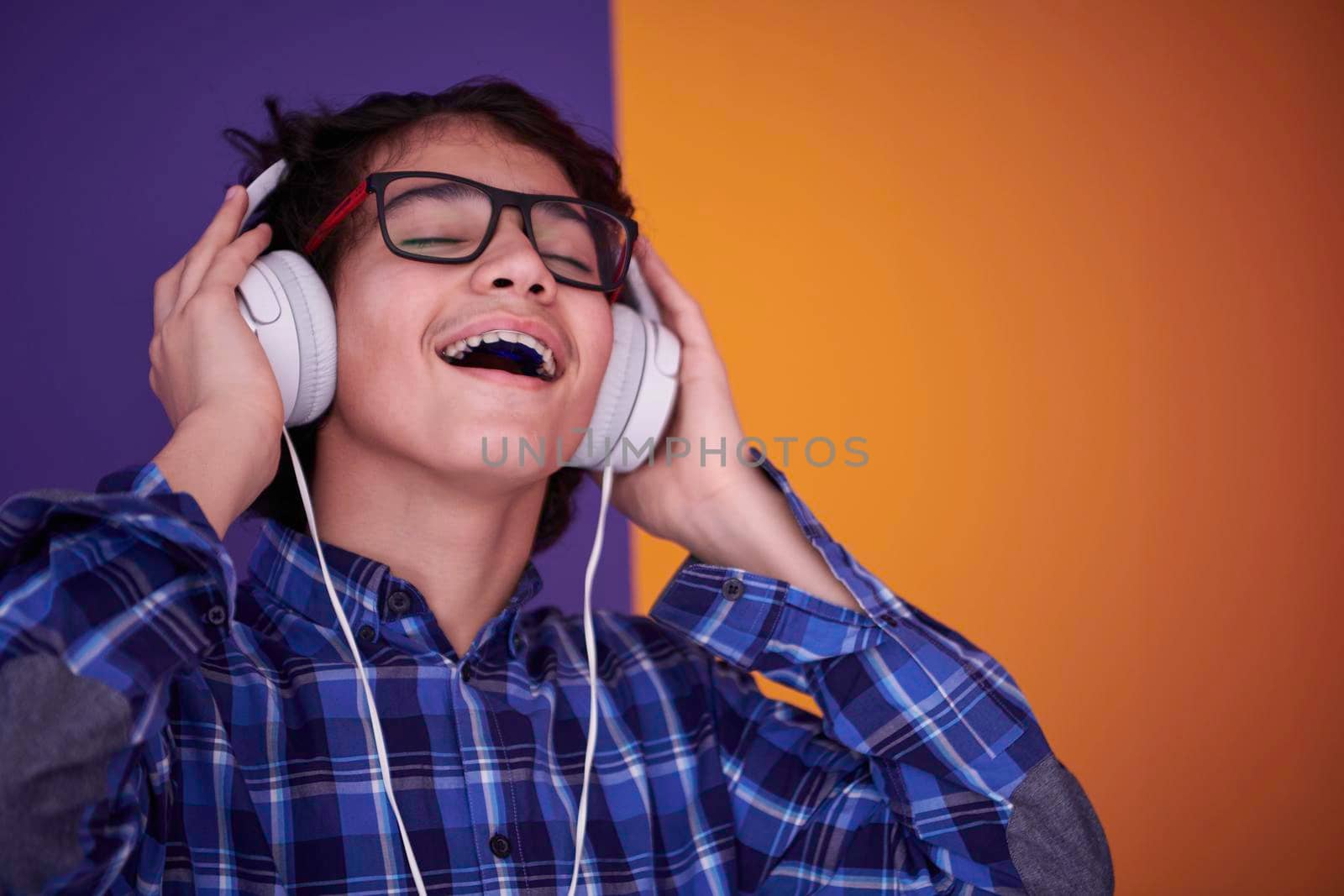 Teenage Boy Wearing Headphones And Listening To Music purple background