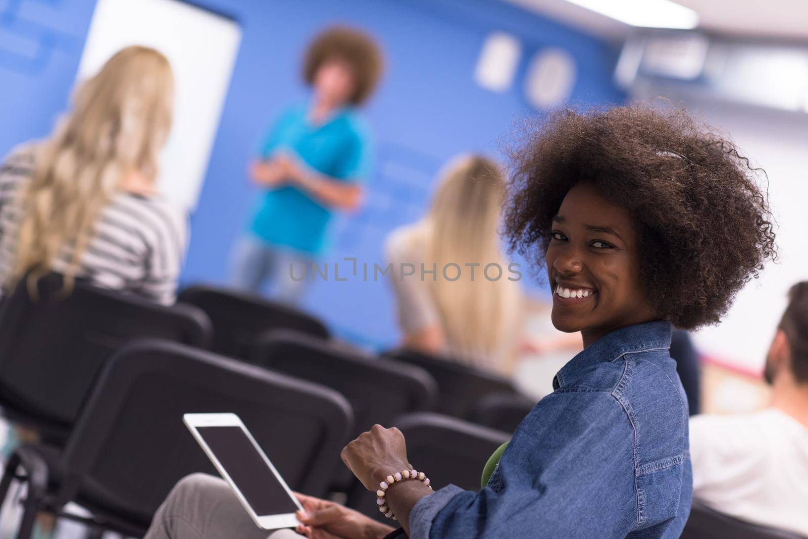 portrait of young African American business woman at modern startup office interior, team in meeting in background