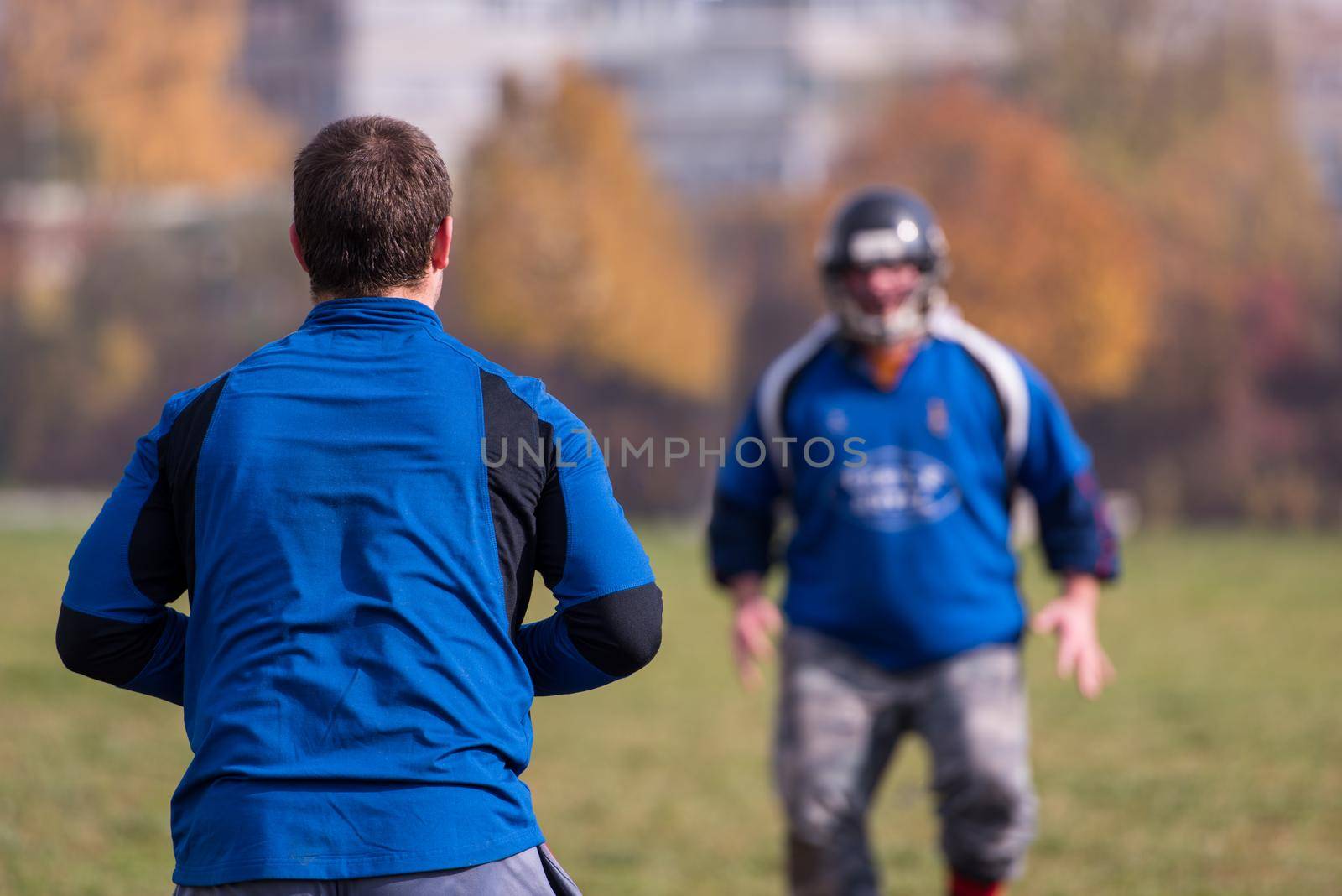Team coach throwing the ball into the group of young american football players in action during the training at the field