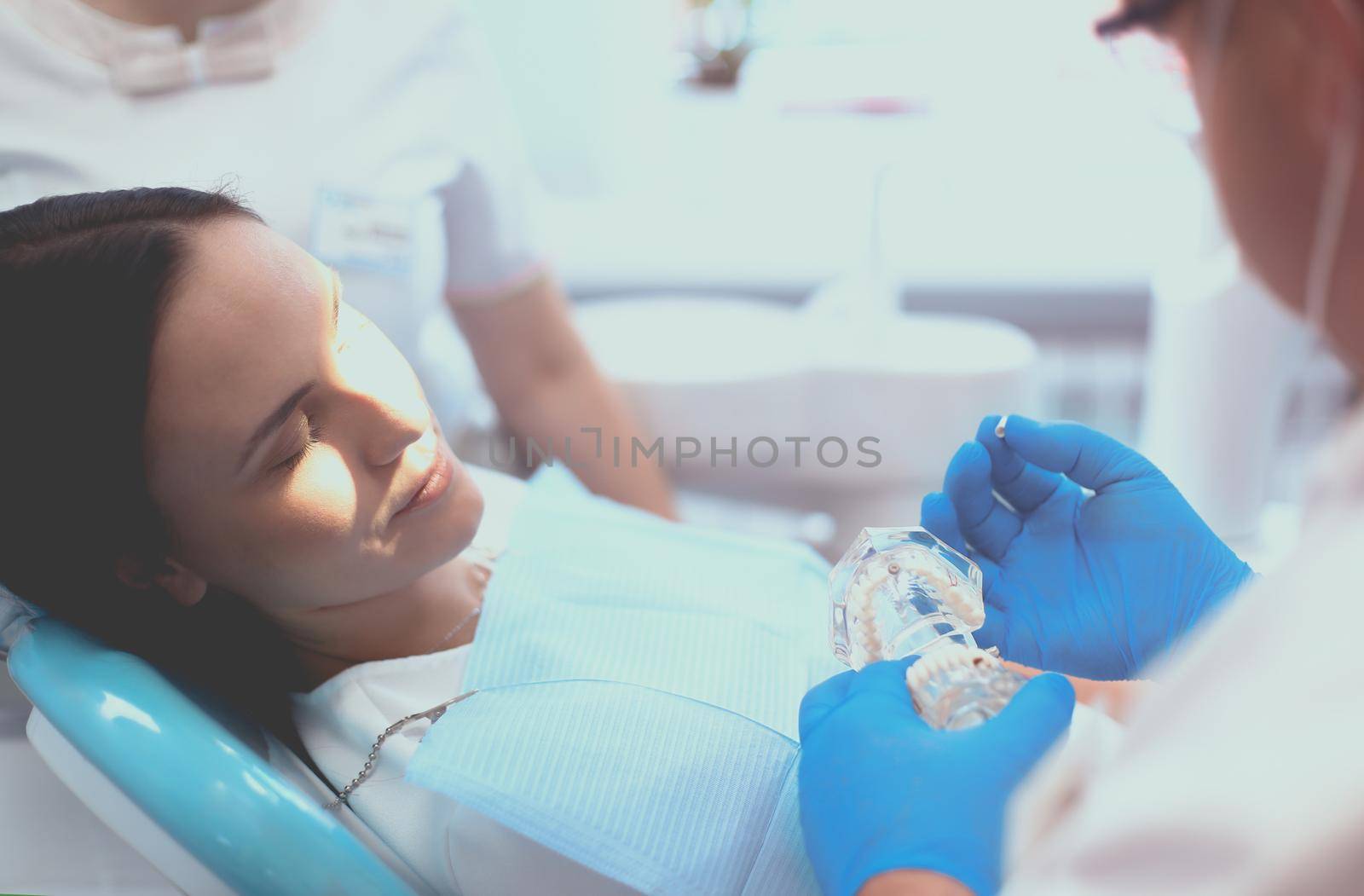 Portrait of a dentist who treats teeth of young woman patient by lenets