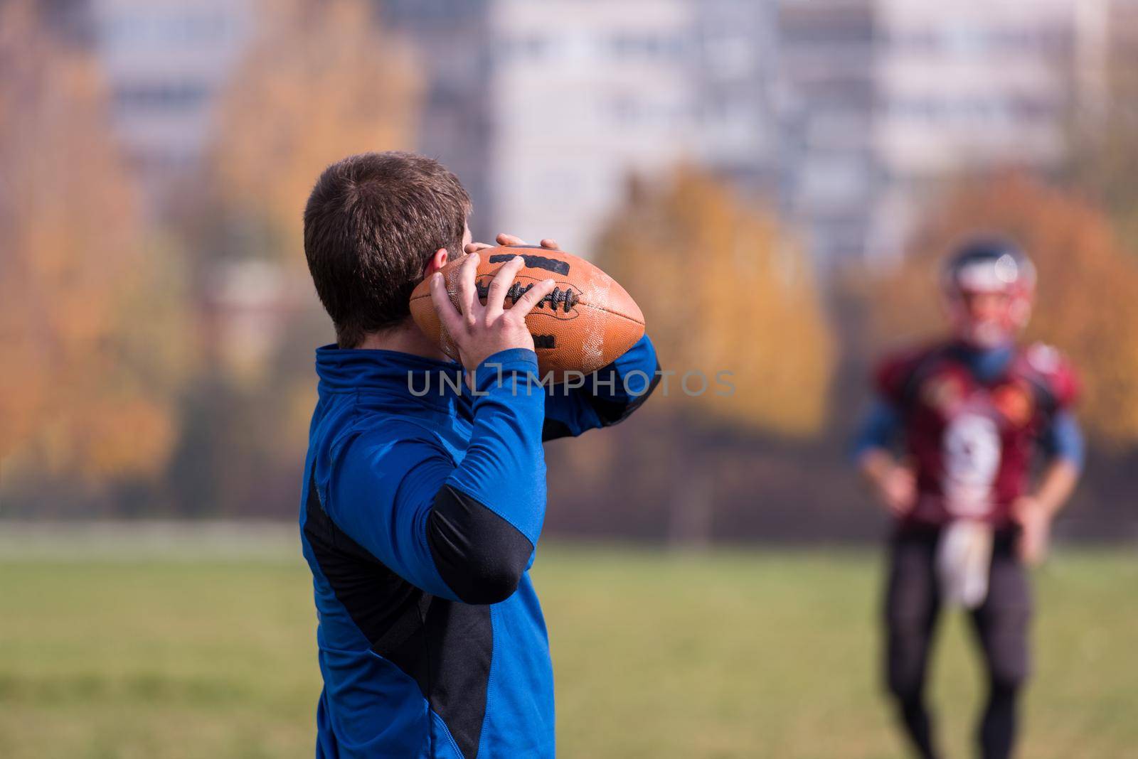 Team coach throwing the ball into the group of young american football players in action during the training at the field