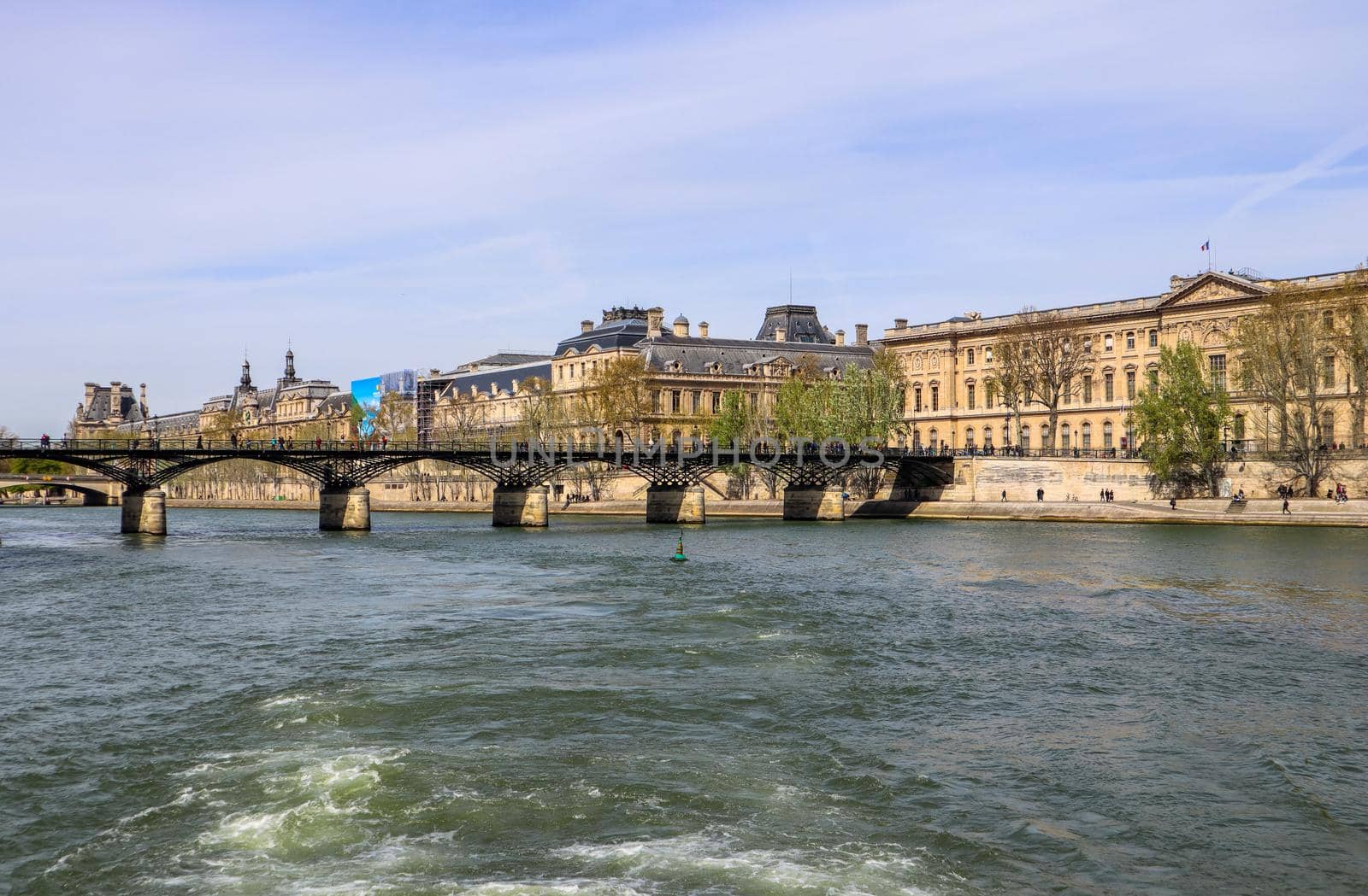 Pedestrian bridge (Pont des Arts) over Seine river and historic buildings of Paris France