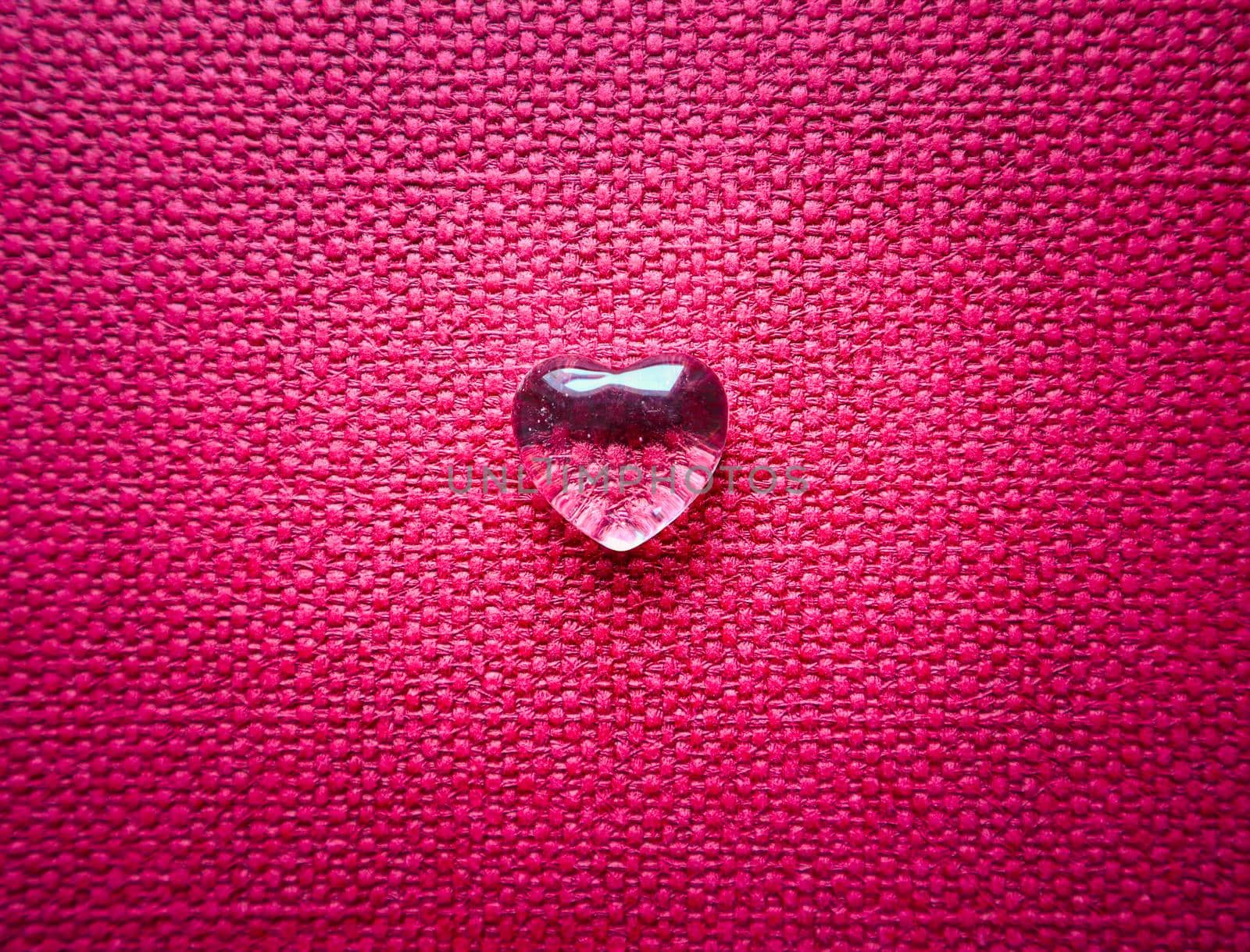 A transparent heart on backdrop of pink textile texture. Perfect Valentine's Day greeting card background.