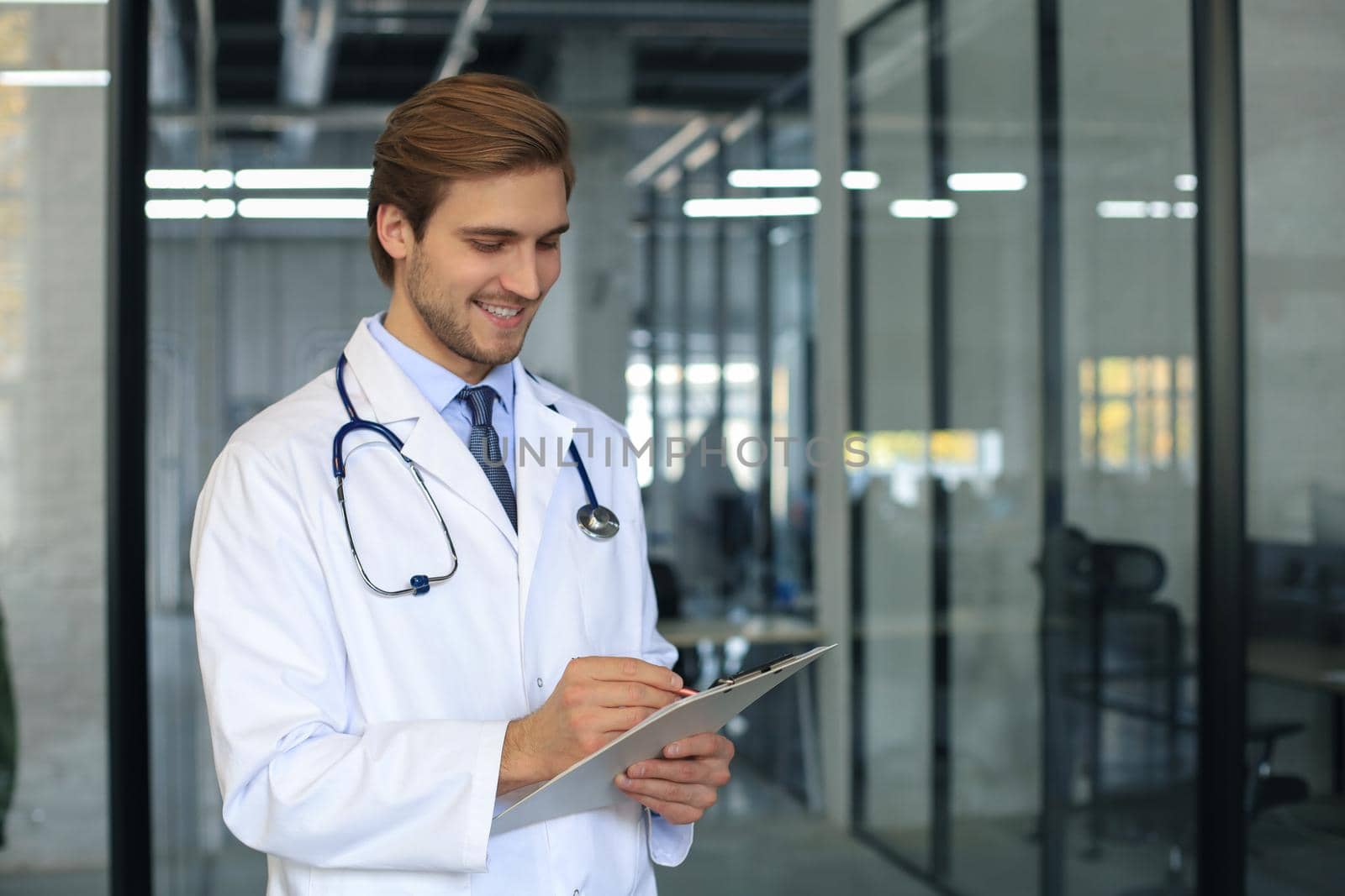 Portrait of doctor standing in hospital corridor wearing lab coat and stethoscope