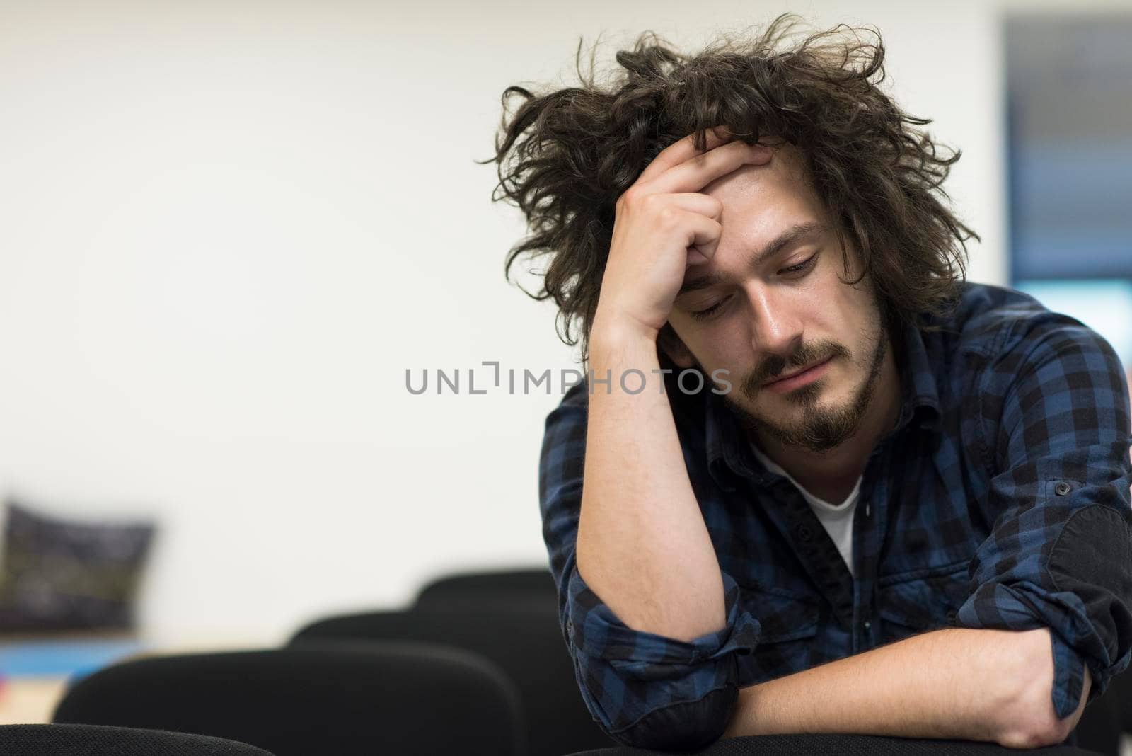 A student sits alone in a empty seats in a classroom