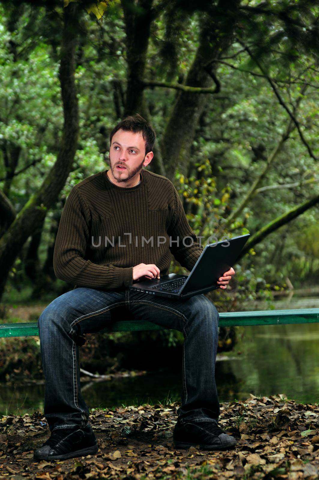 one young businessman working on laptop outdoor with green nature in background