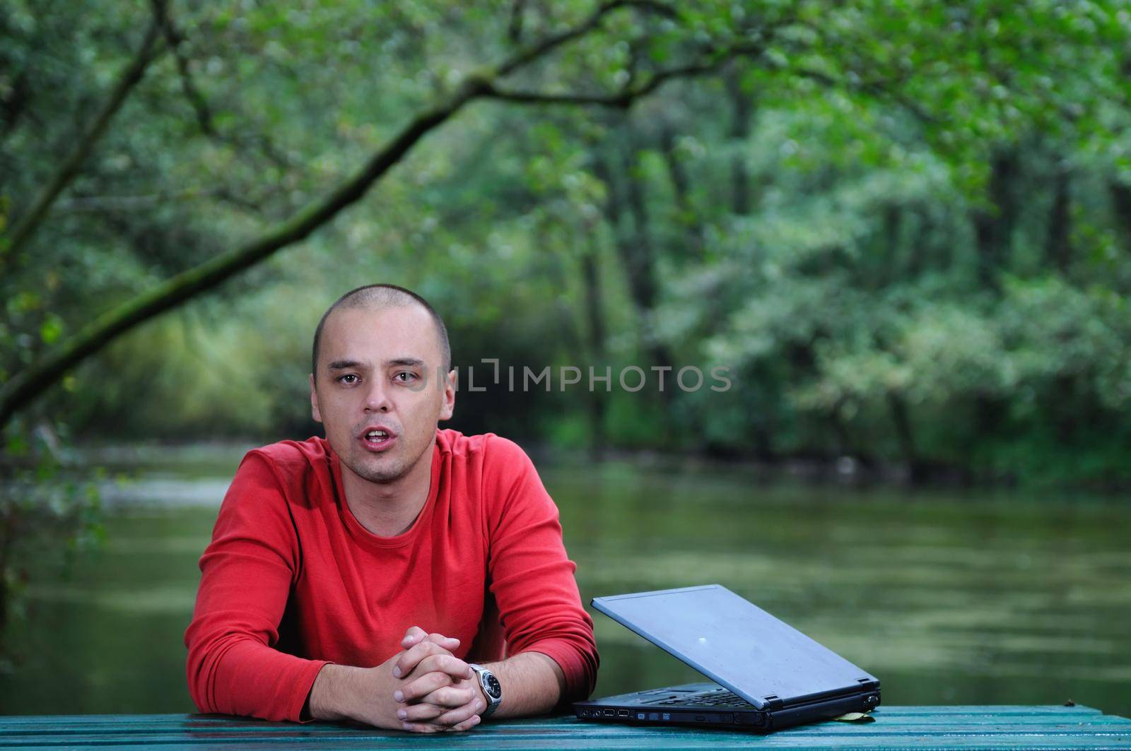 one young businessman working on laptop outdoor with green nature in background