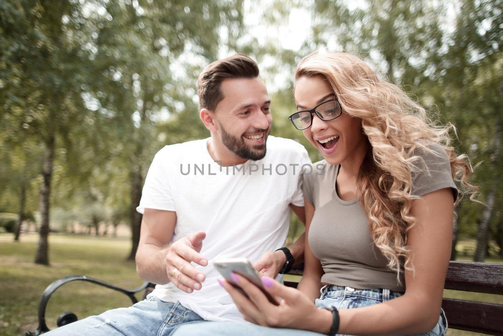 young couple discussing something sitting on a bench in the Park.people and technology