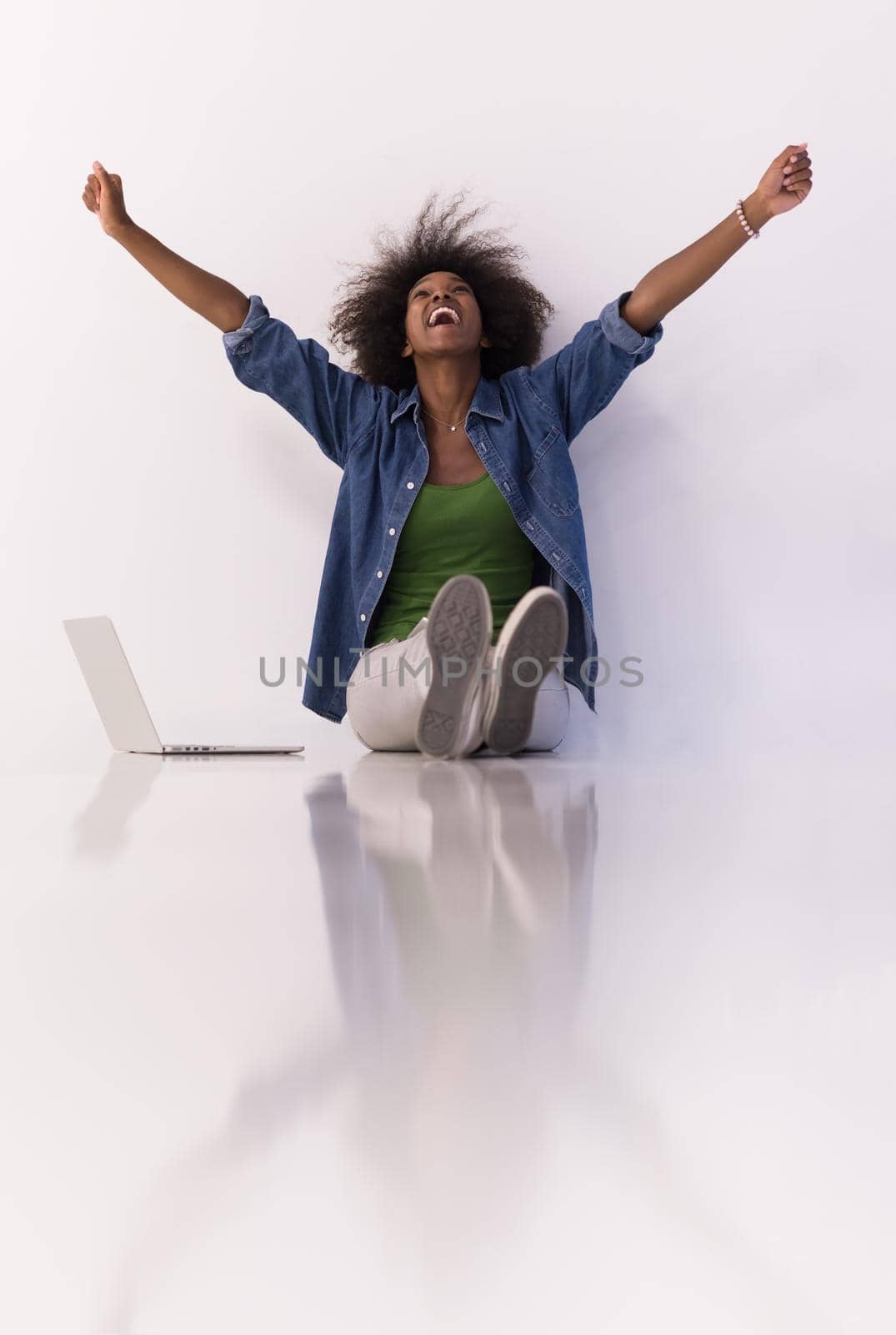 Portrait of happy young african american woman sitting on floor with laptop