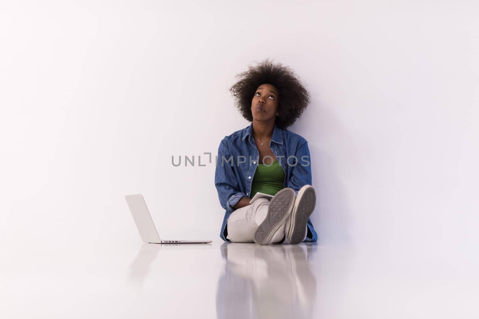 Portrait of happy young african american woman sitting on floor with laptop