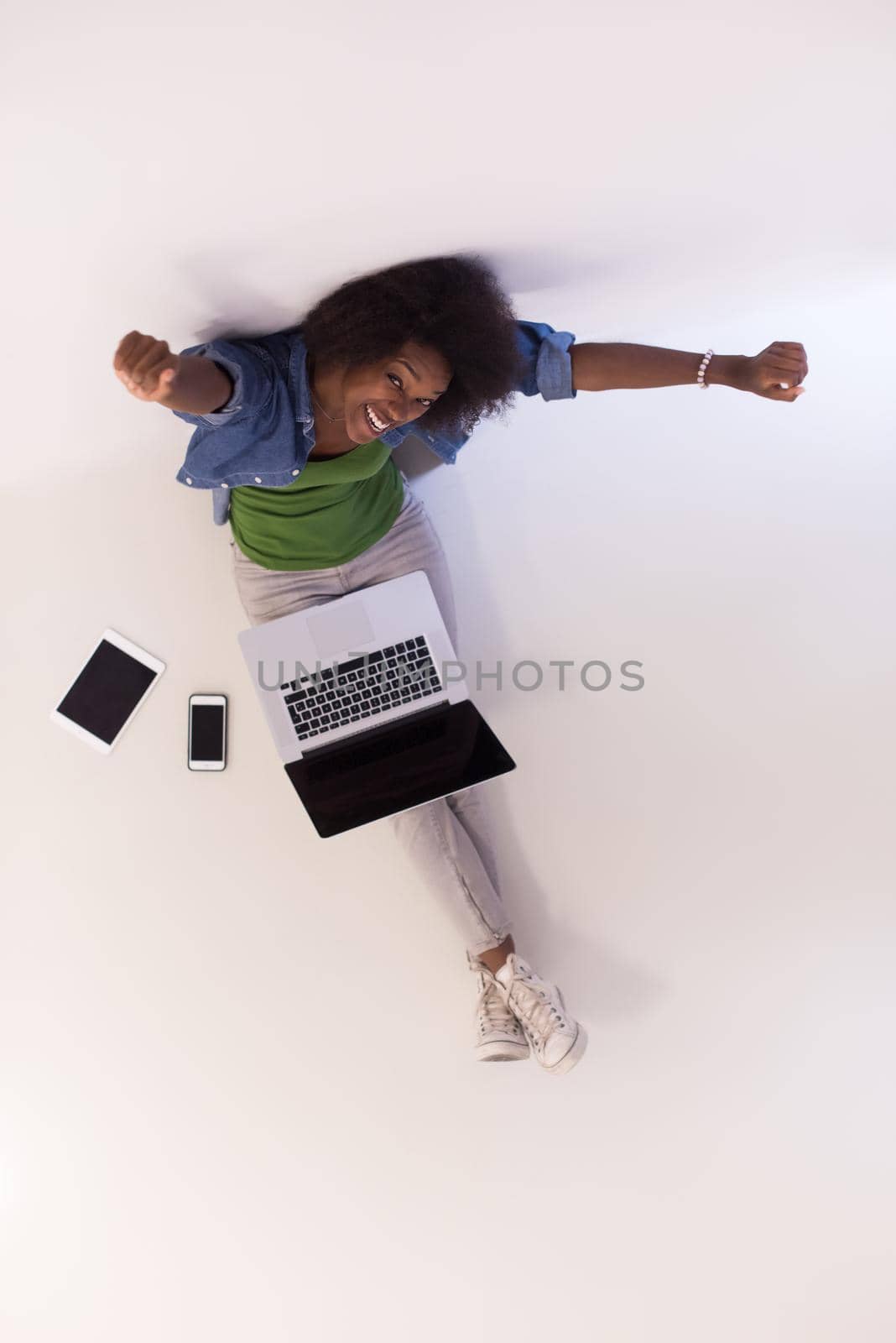 african american woman sitting on floor with laptop top view by dotshock