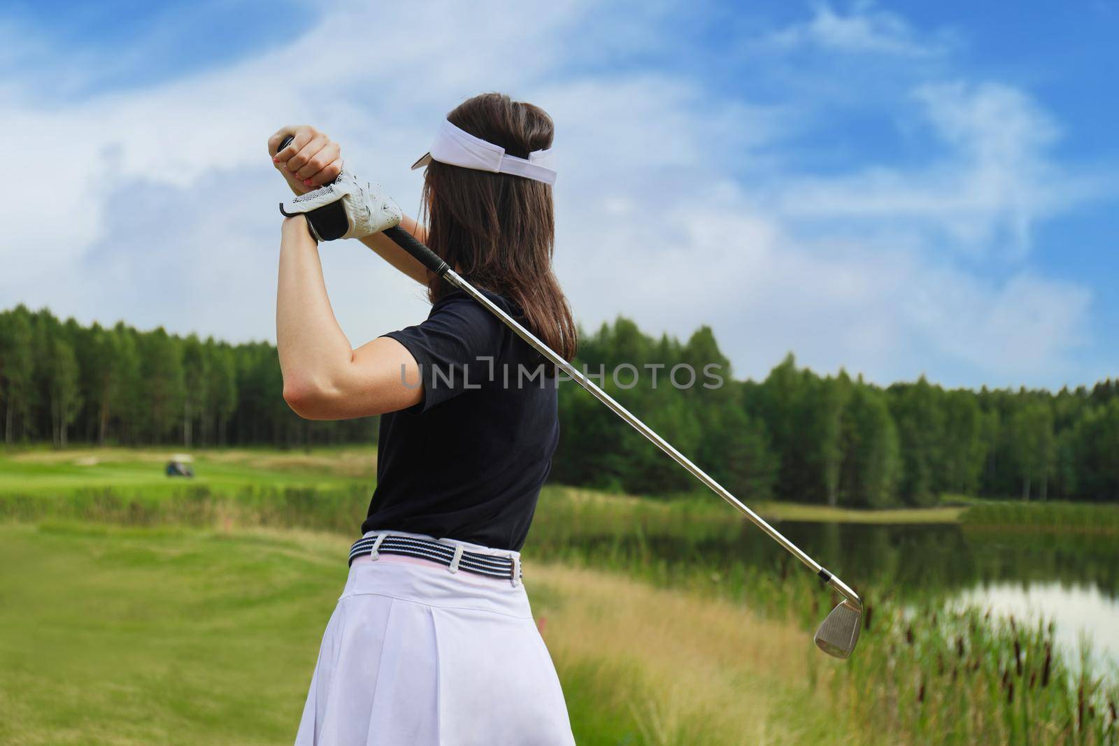 Woman golfer hits an fairway shot towards the club house