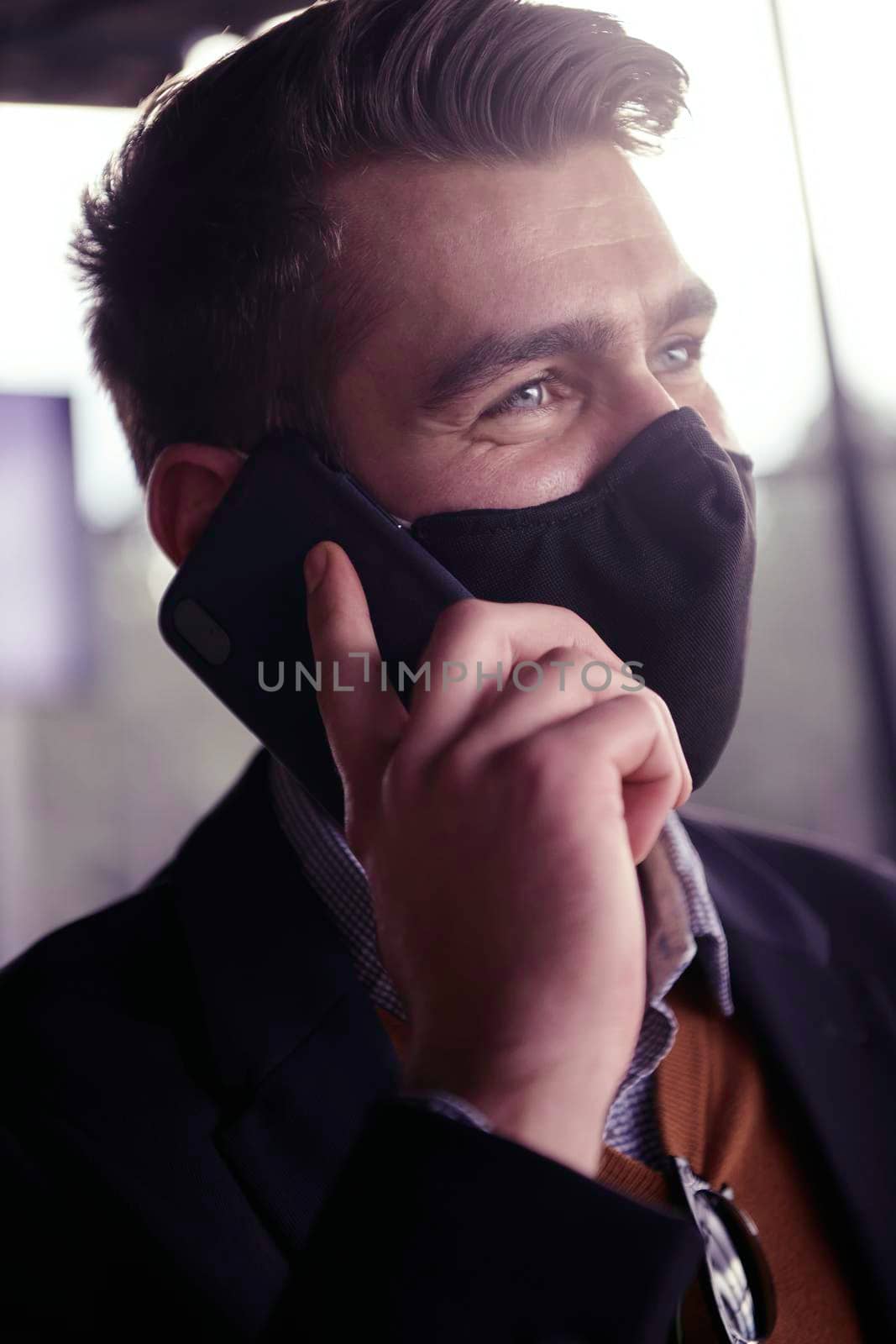 business man wearing coronavirus  medical face mask while using smartphone by dotshock
