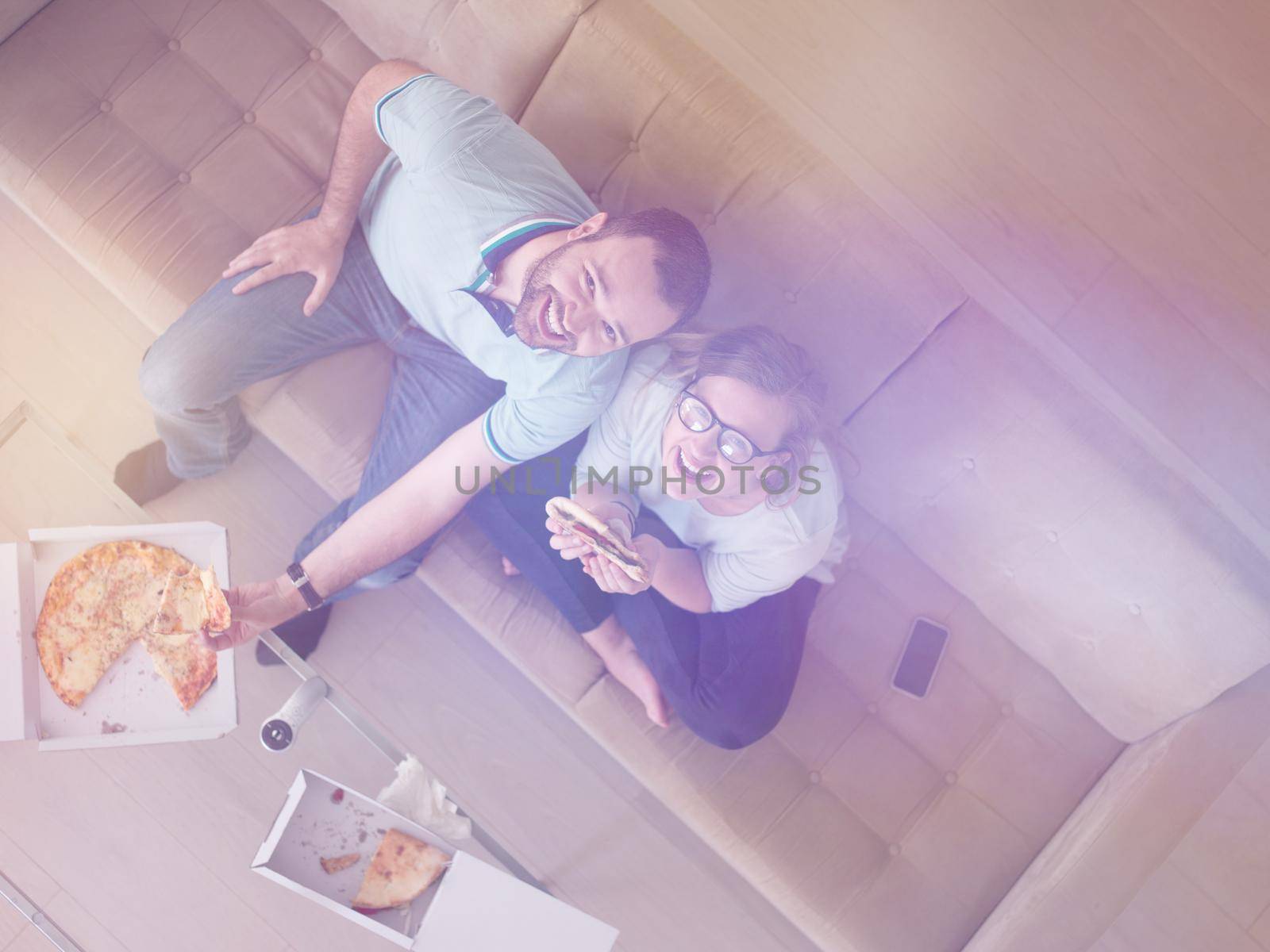 couple eating pizza in their luxury home villa by dotshock