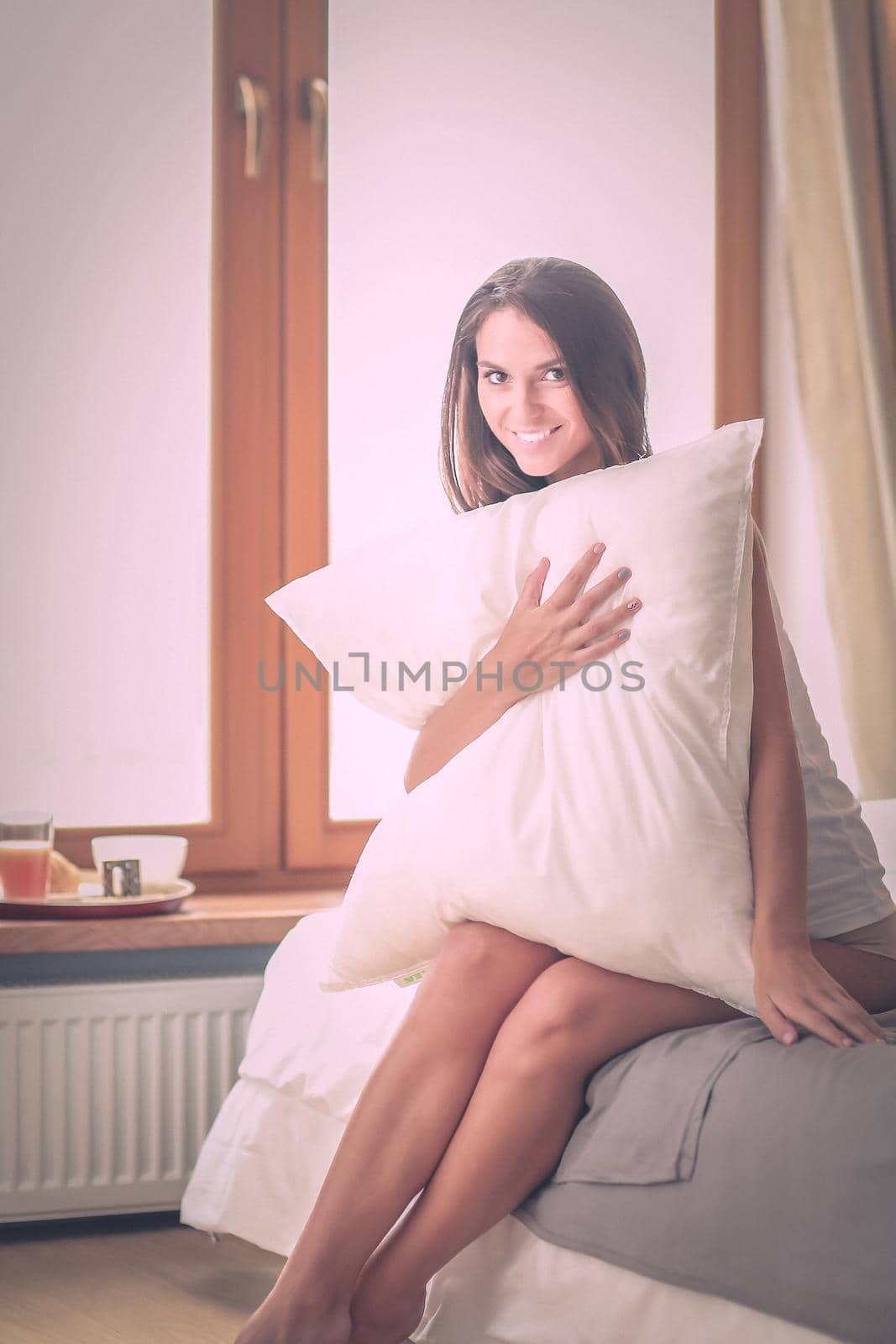 Young woman sitting in bed with a cup of milk.