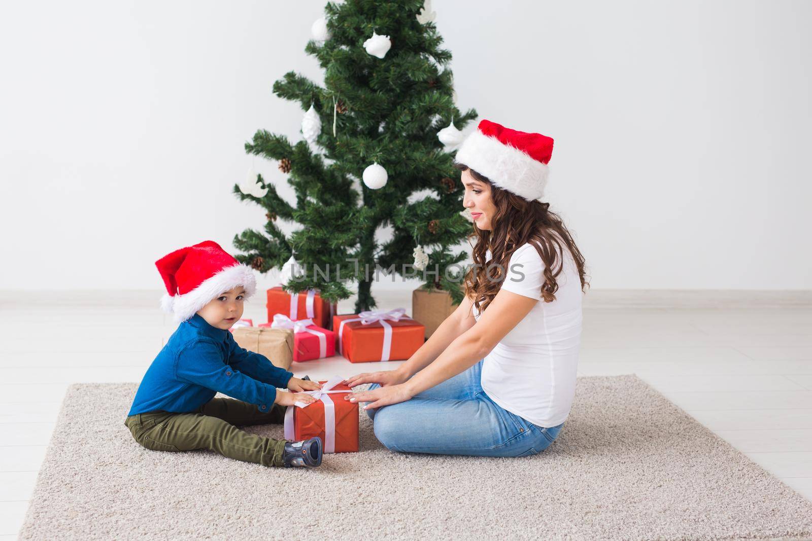 Christmas, single parent and holidays concept - Cute little boy holding christmas present for his mother at the home