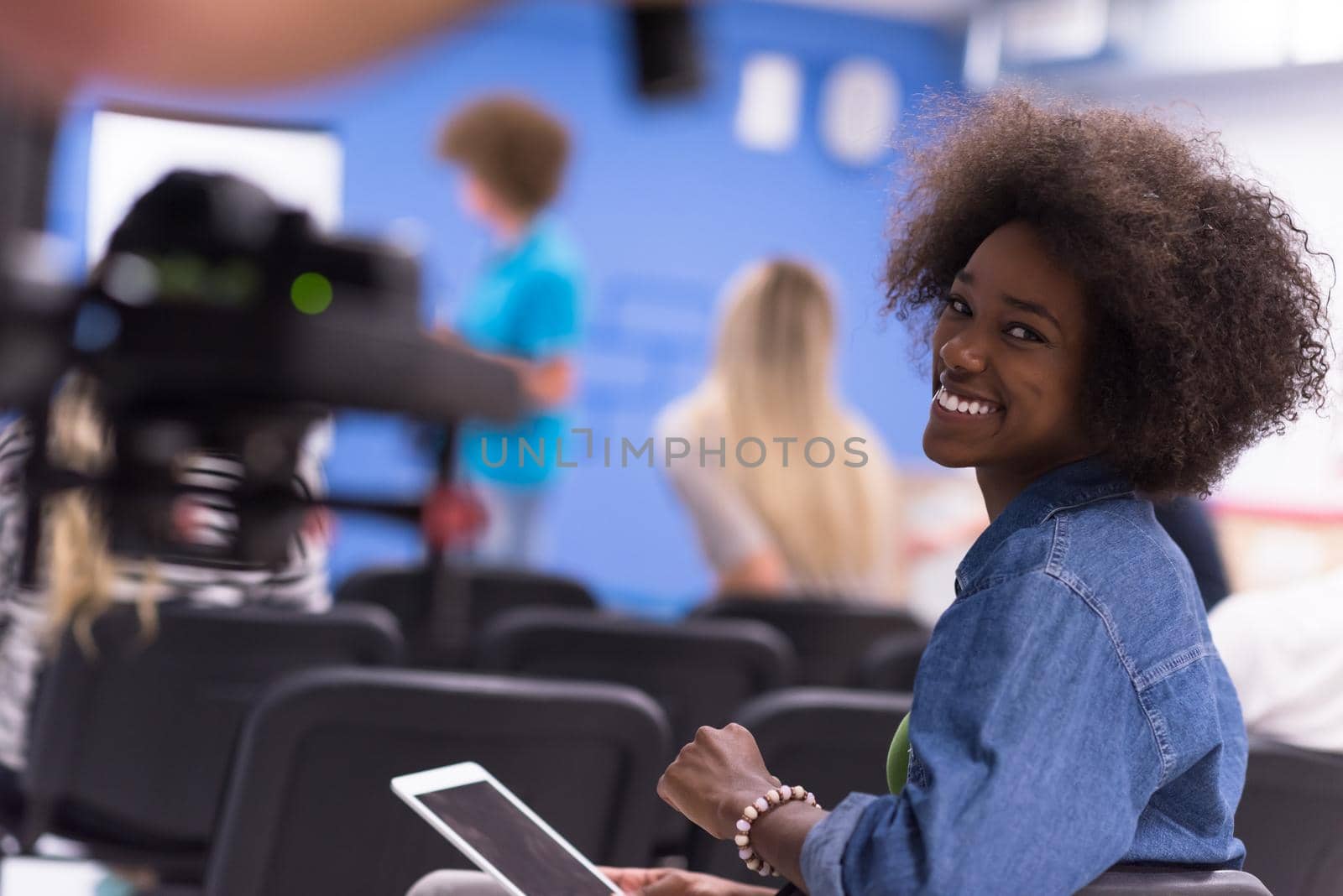 portrait of young African American business woman at modern startup office interior, team in meeting in background
