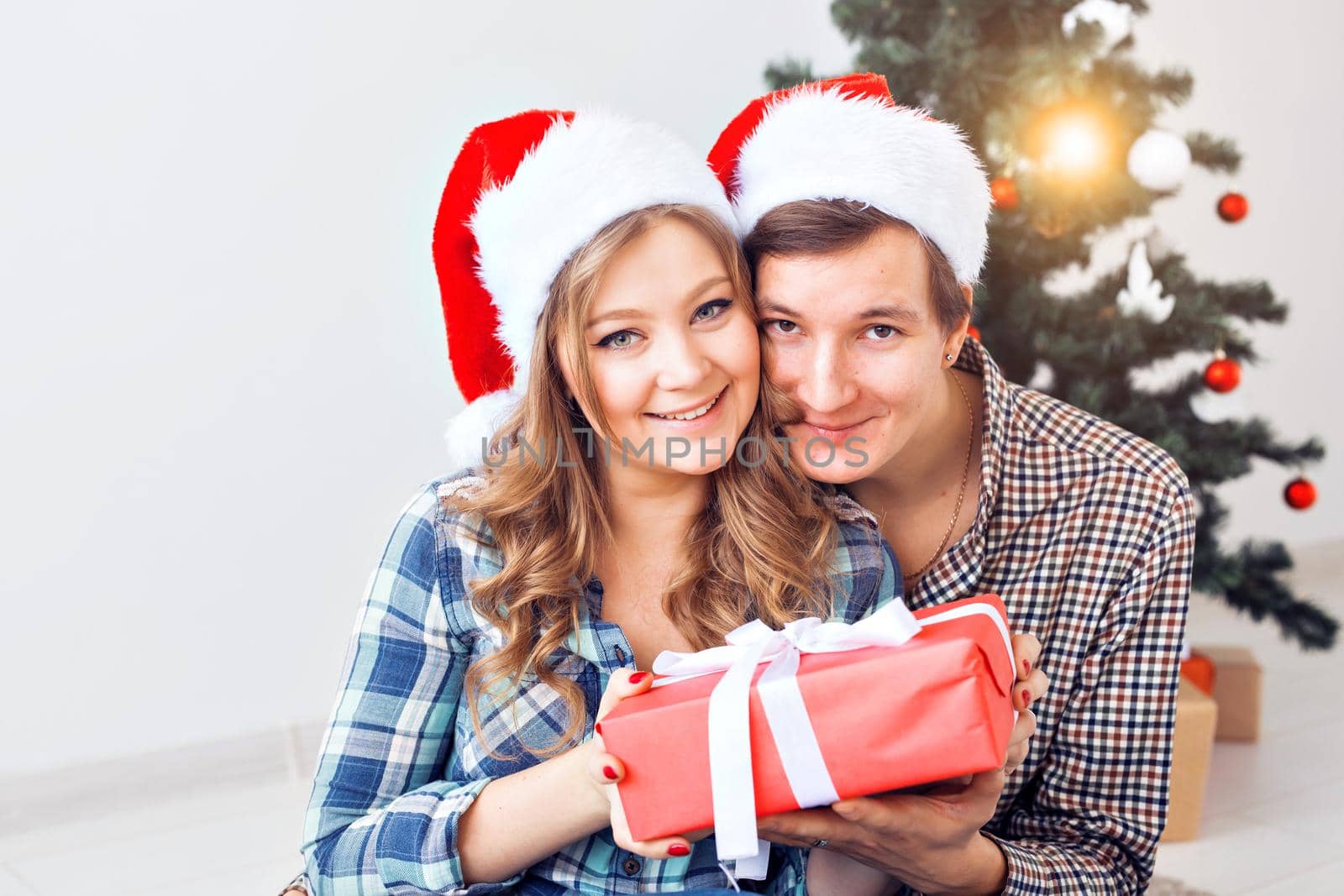 Family, x-mas, winter holidays and people concept - happy couple hugging near christmas tree at home.
