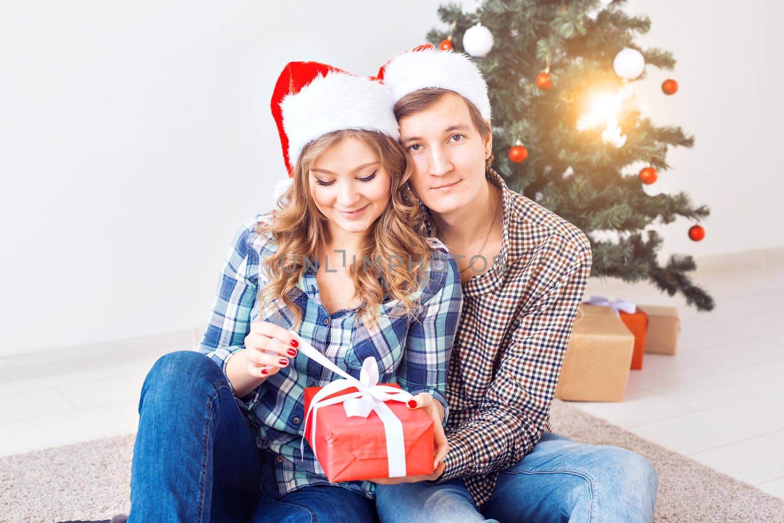 Family, x-mas, winter holidays and people concept - happy couple hugging near christmas tree at home.