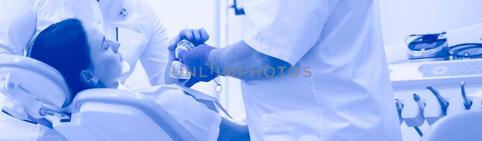 Male dentists examining and working on young female patient.Dentist's office