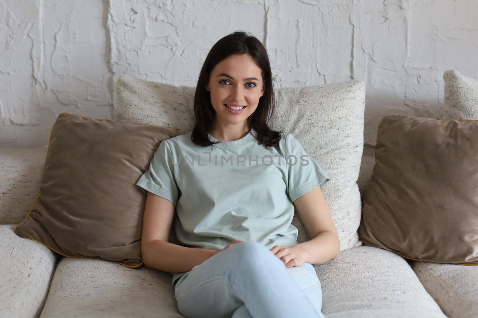 Beautiful young woman sitting on sofa, indoors