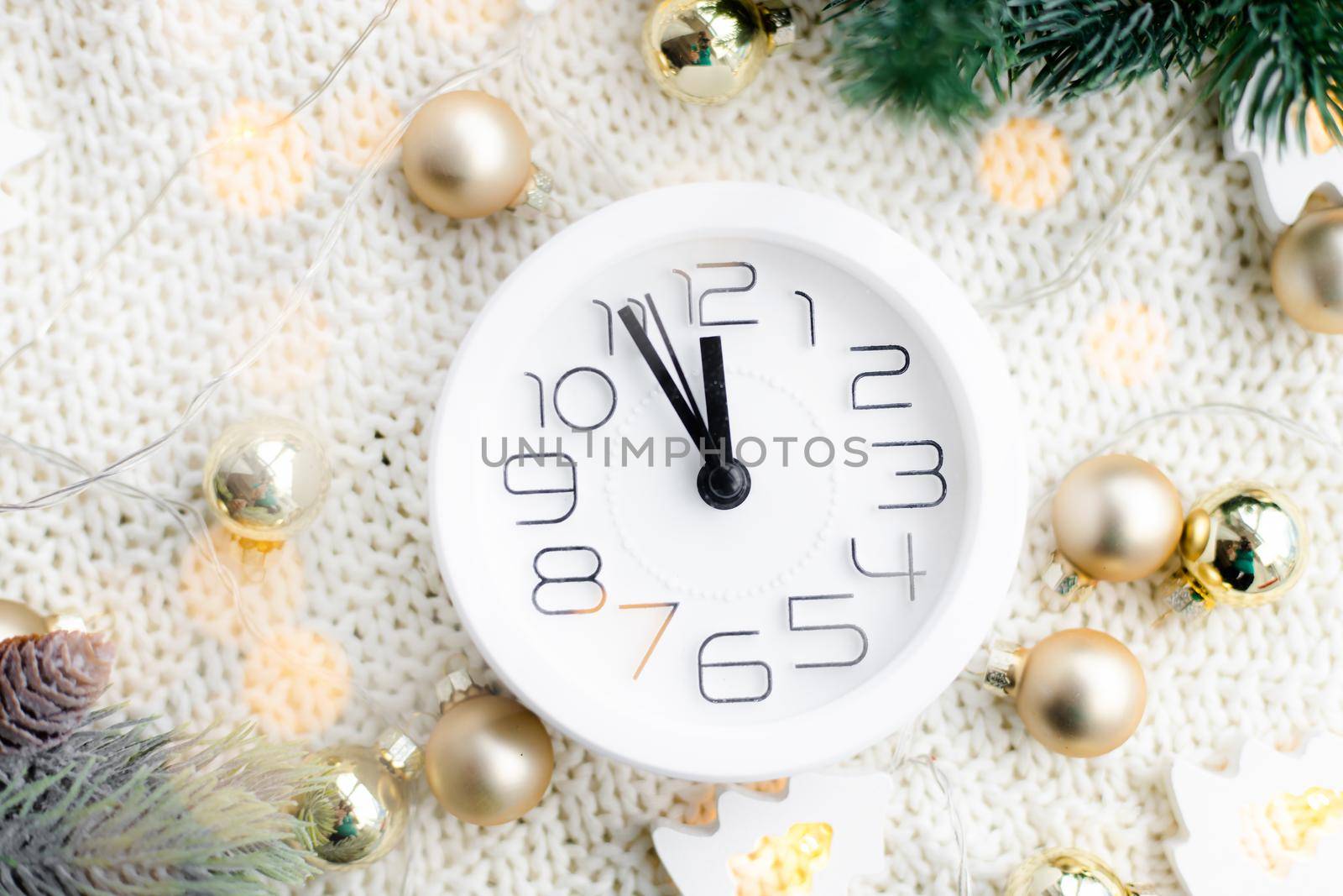 A clock on the beach with a garland . A white watch. Cozy vibes . Home comfort. New Year and Christmas. Decorating