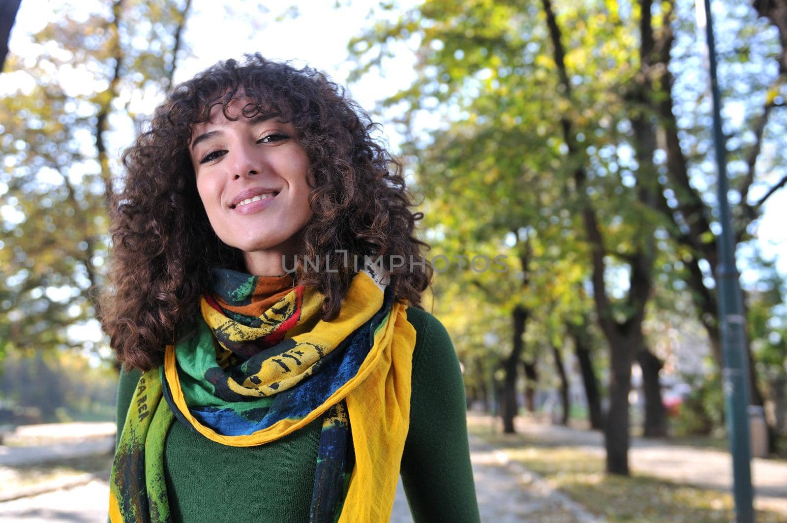 brunette Cute young woman with colorful scarf smiling outdoors in nature
