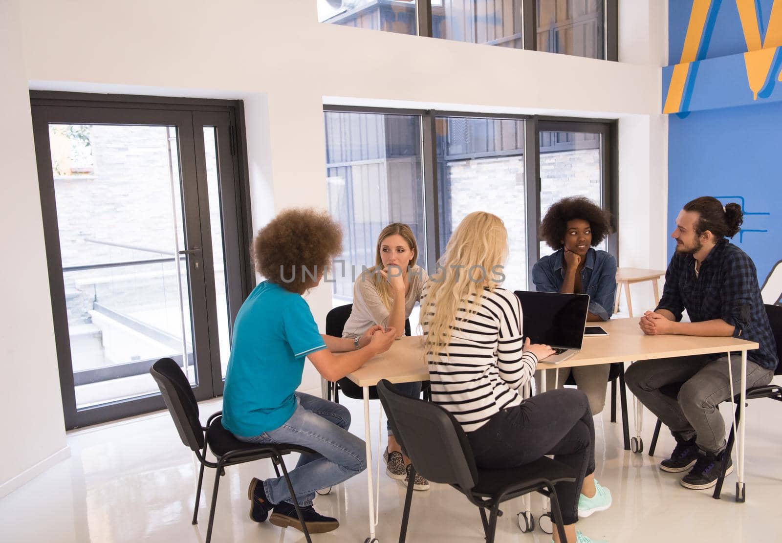 Multiethnic startup business team on meeting in modern bright office interior brainstorming, working on laptop and tablet computer