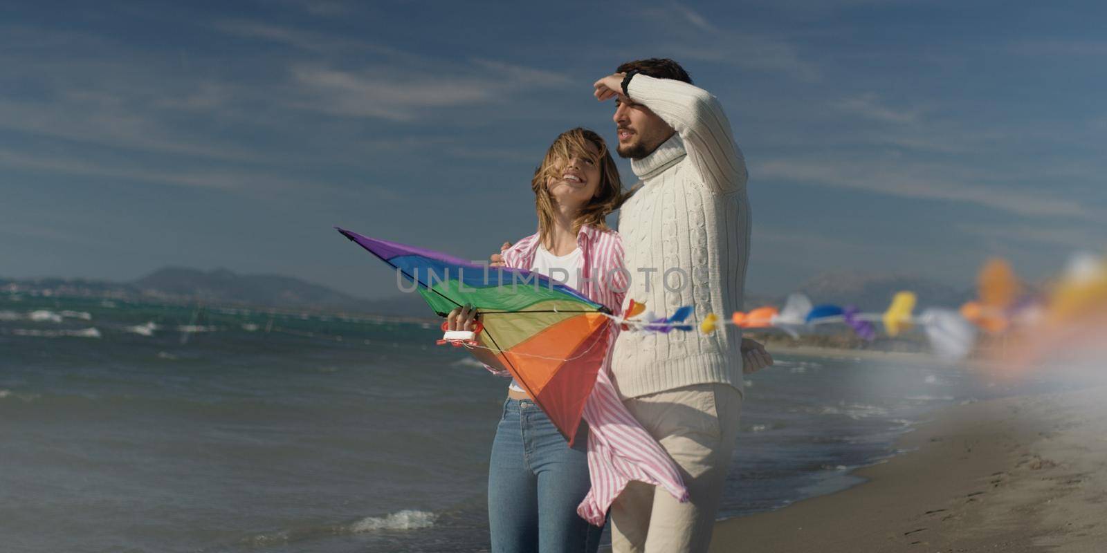 Happy couple having fun with kite on beach by dotshock