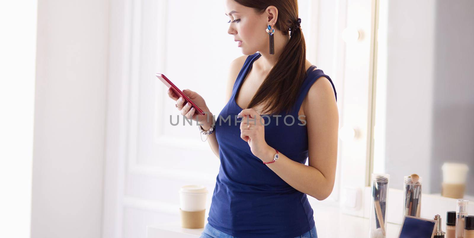 Woman beauty salon using and looking at mobile phone.