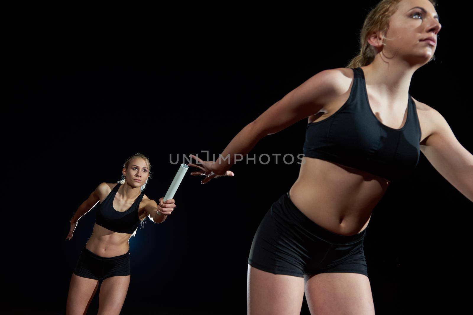 woman athletic runners passing baton in relay race