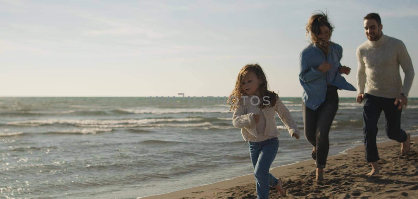 Family with kids resting and having fun at beach during autumn day