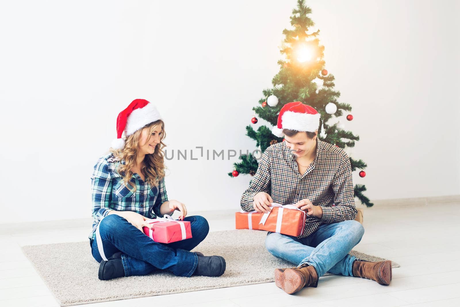 Holidays, christmas and family concept - Young happy couple opening gifts at home