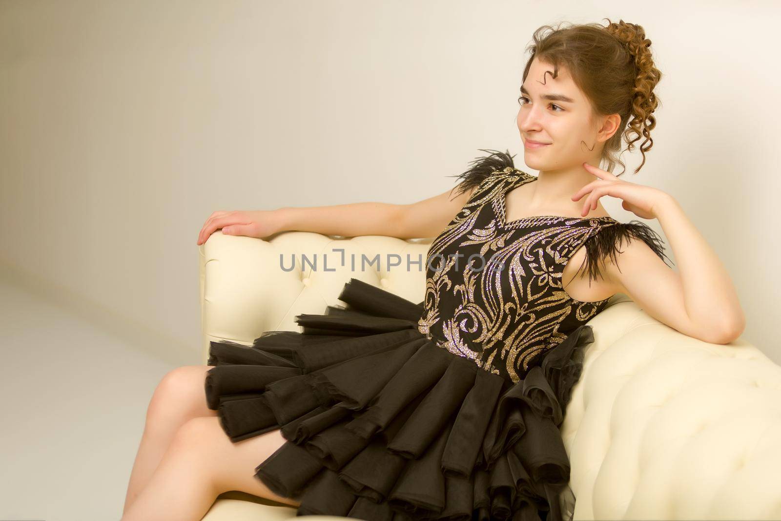 Teen girl in elegant dress sitting on the couch. by kolesnikov_studio