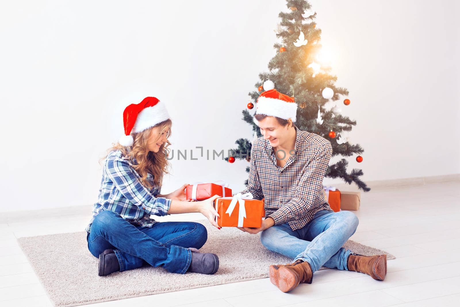 Holidays, christmas and family concept - Young happy couple opening gifts at home. by Satura86