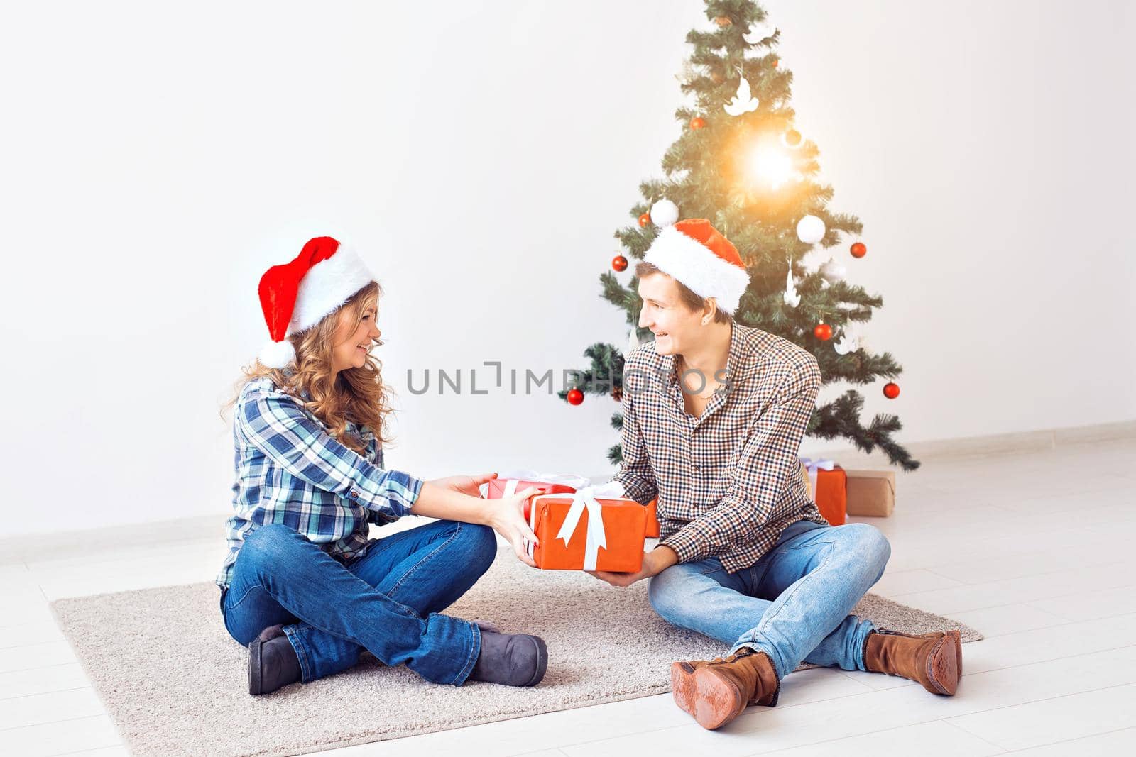 Holidays, christmas and family concept - Young happy couple opening gifts at home