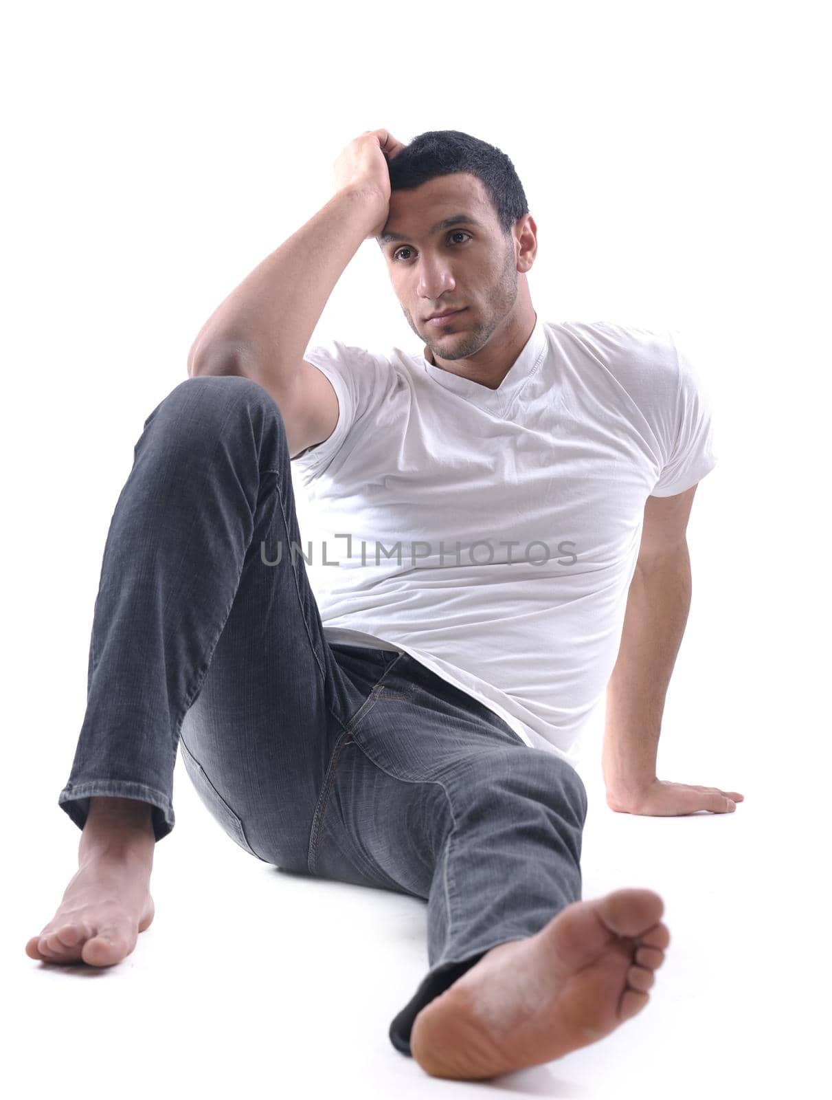 portrait of relaxed young man dressed in white shirt and jeans isolated over white background in studio