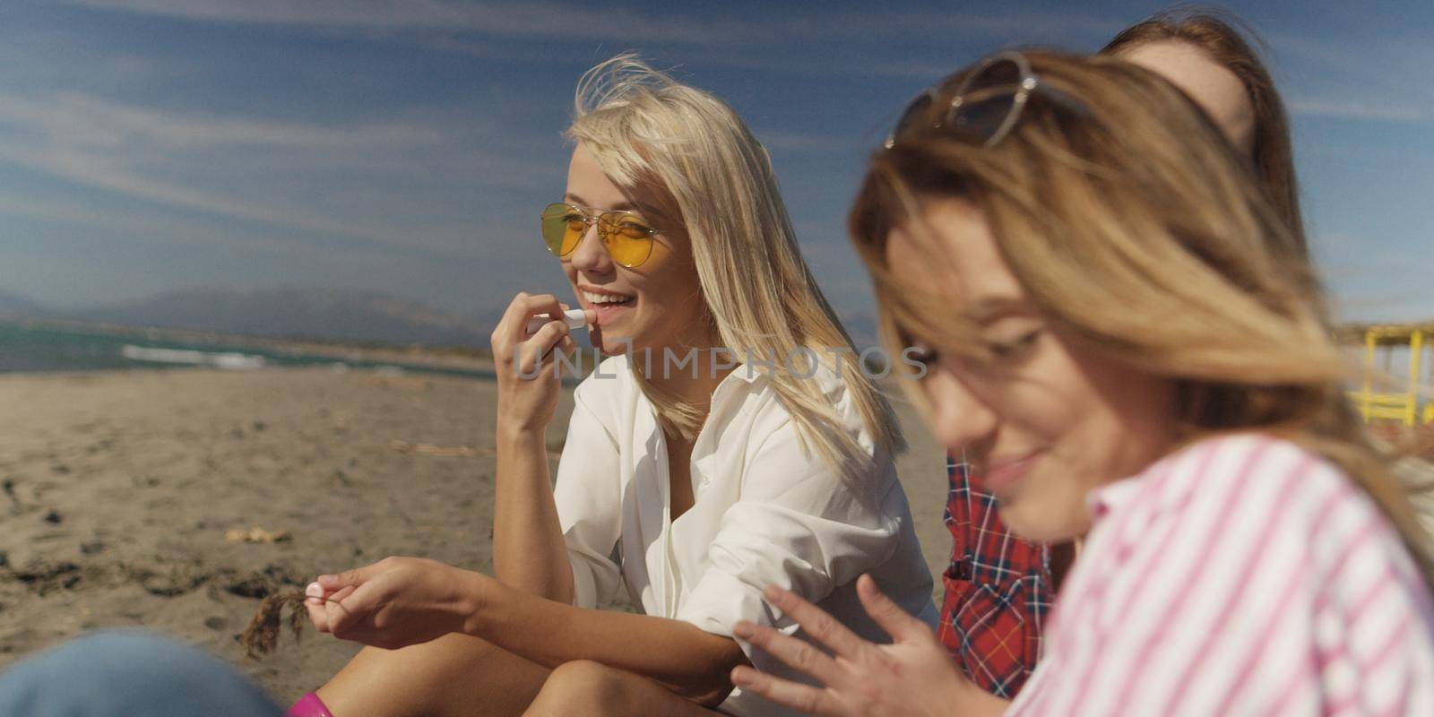 Group of girlfriends having fun on beach during autumn day by dotshock