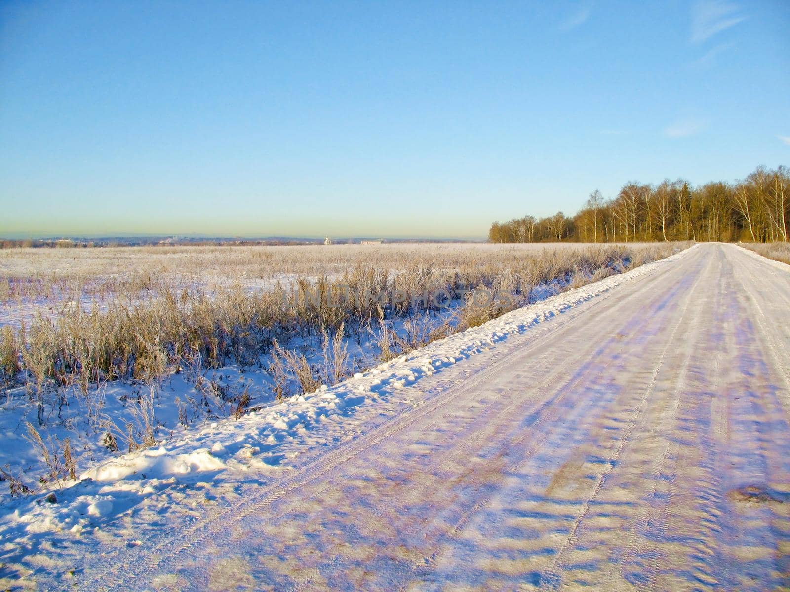 The snow-covered road is an early, sunny, frosty morning in the suburbs.
