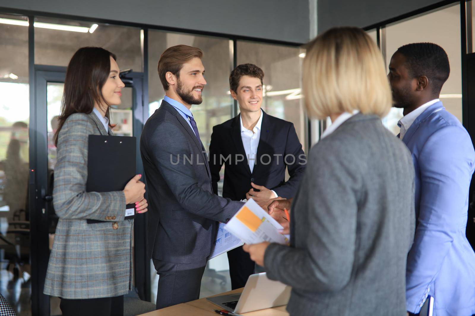 Confident business people shaking hands at workplace. by tsyhun