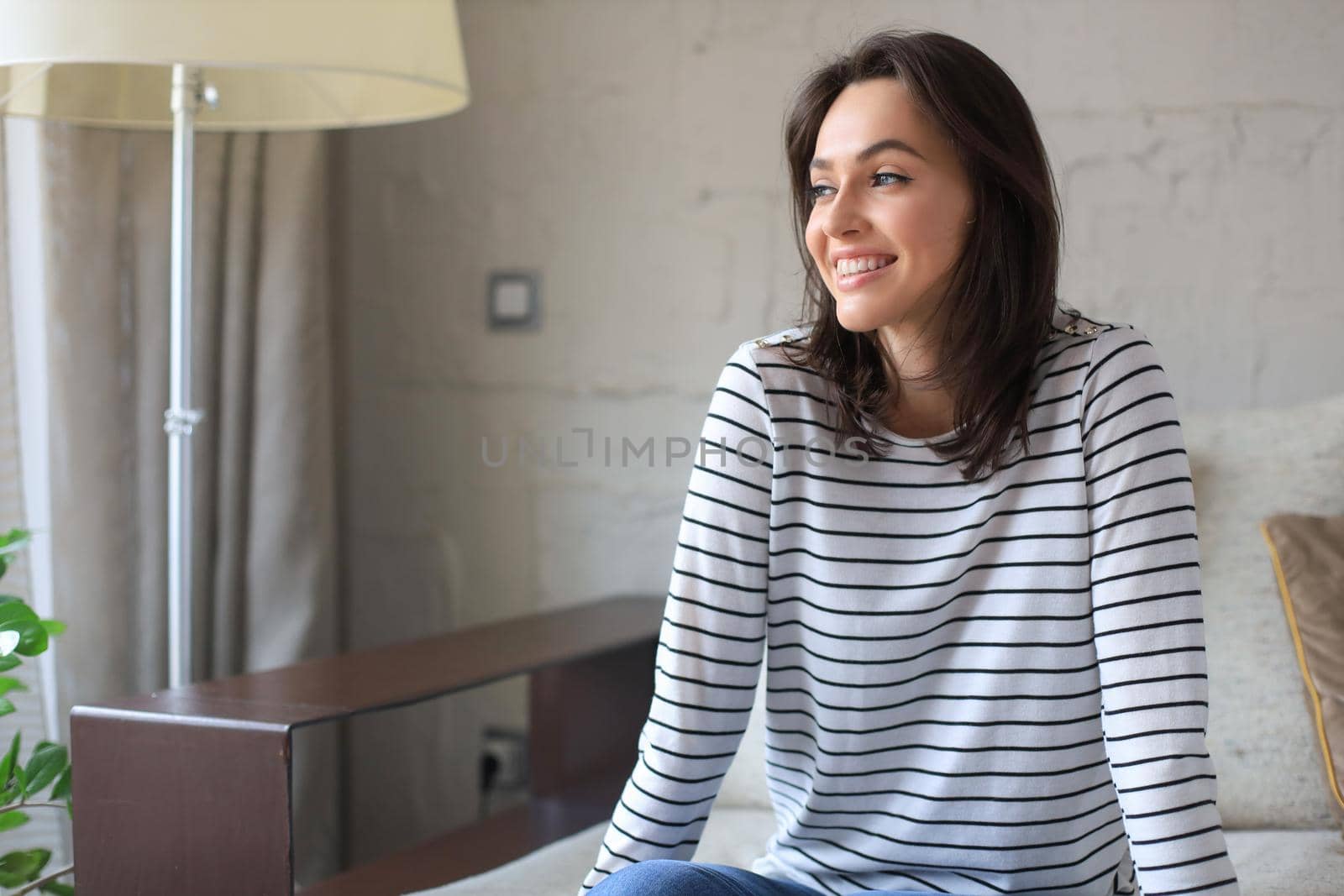 Beautiful young woman sitting on sofa, indoors