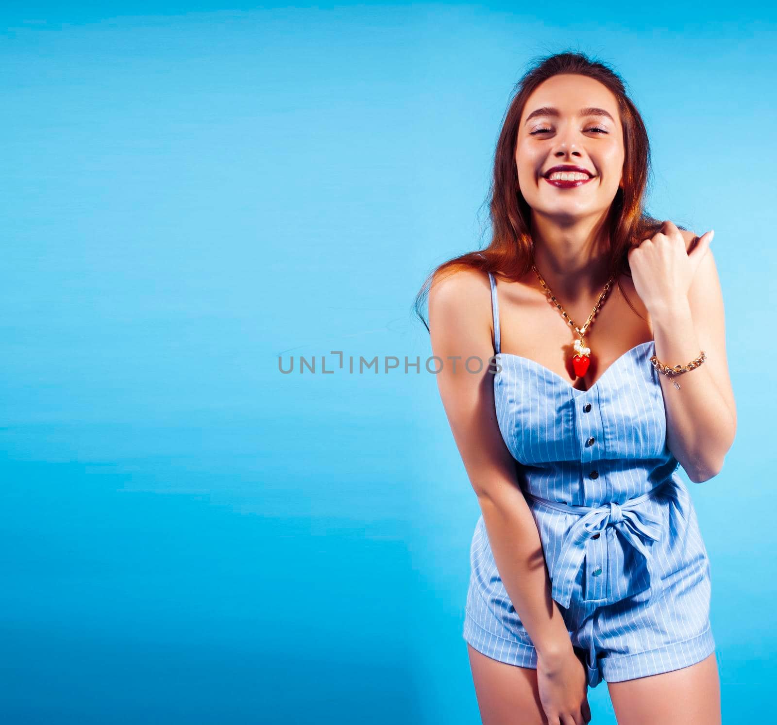 young pretty girl in sunglasses posing happy smiling on blue background, lifestyle people on summer vacation concept close up