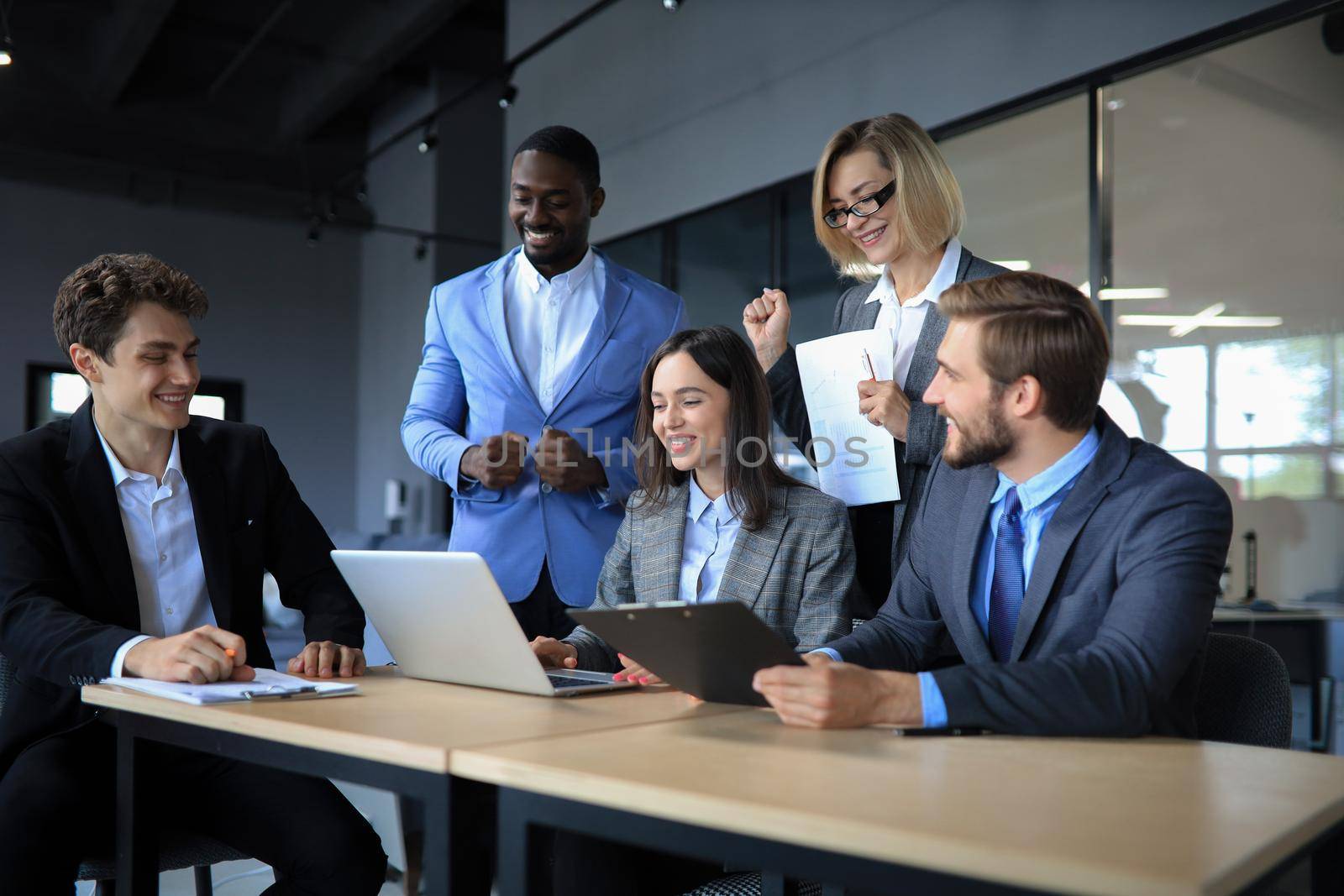 Happy business people laugh near laptop in the office. Successful team coworkers joke and have fun together at work